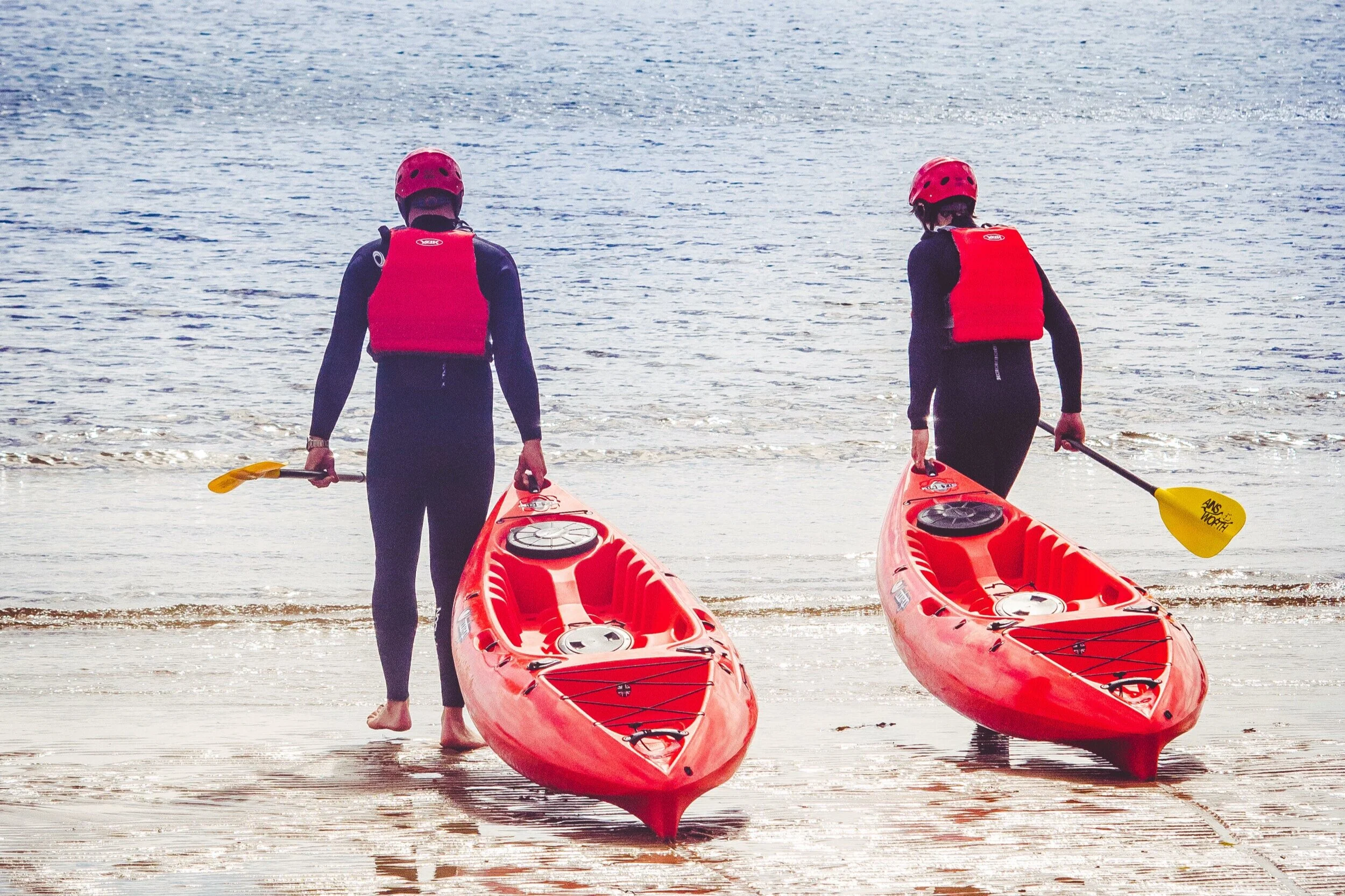 Two people pulling kayaks into the North Sea
