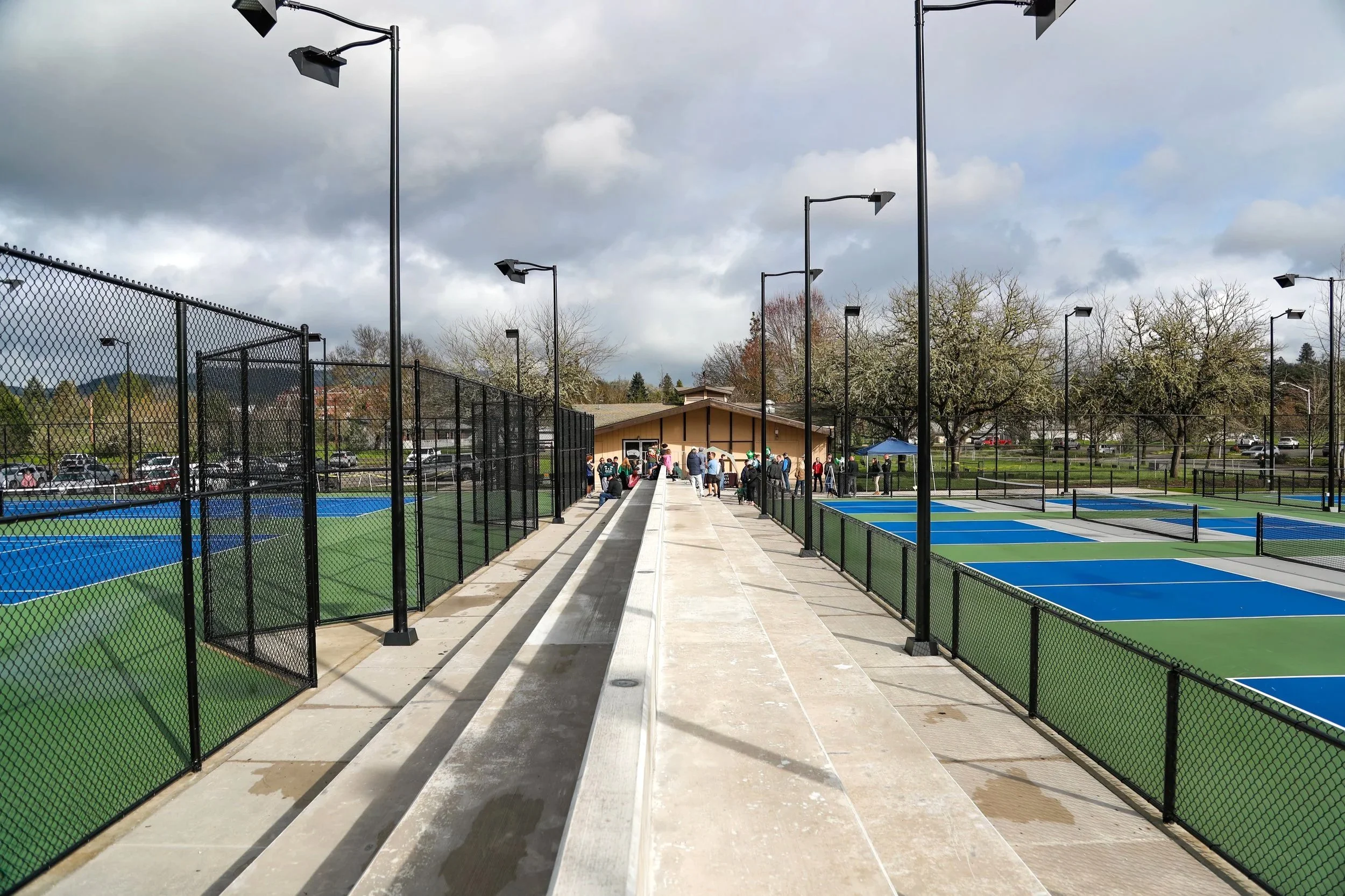 Concrete seating between the outdoor tennis and pickleball courts