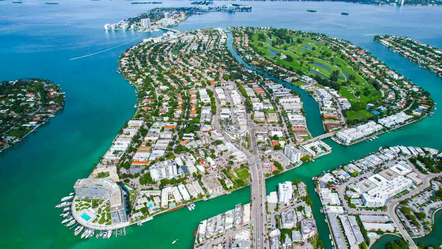 Aerial view of a coastal city with waterways, high-rise buildings, residential neighborhoods, and green parks.