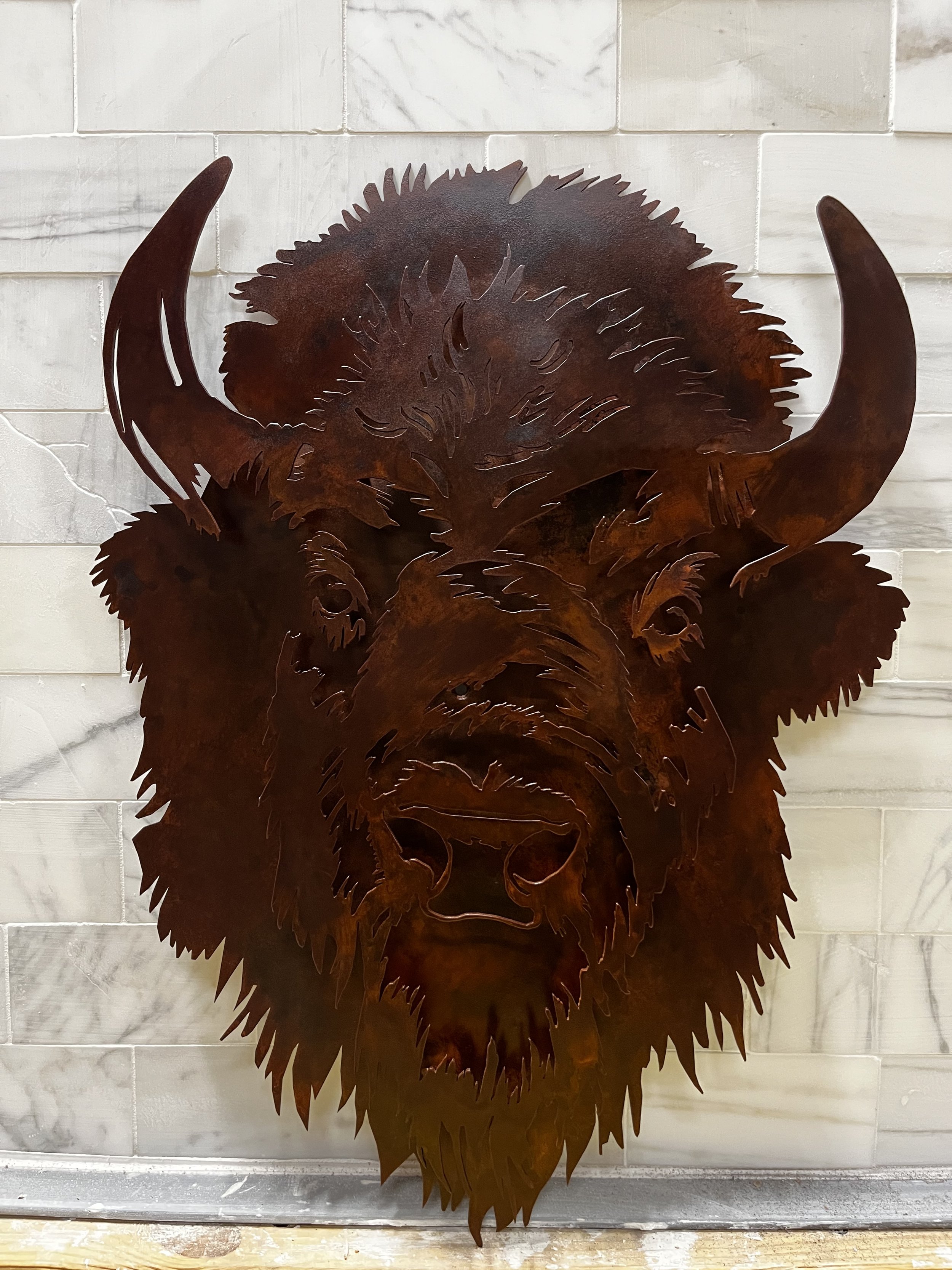 Layered low relief sculpture of American bison.  The buffalo is made of solid steel and has a rusted patina finish.