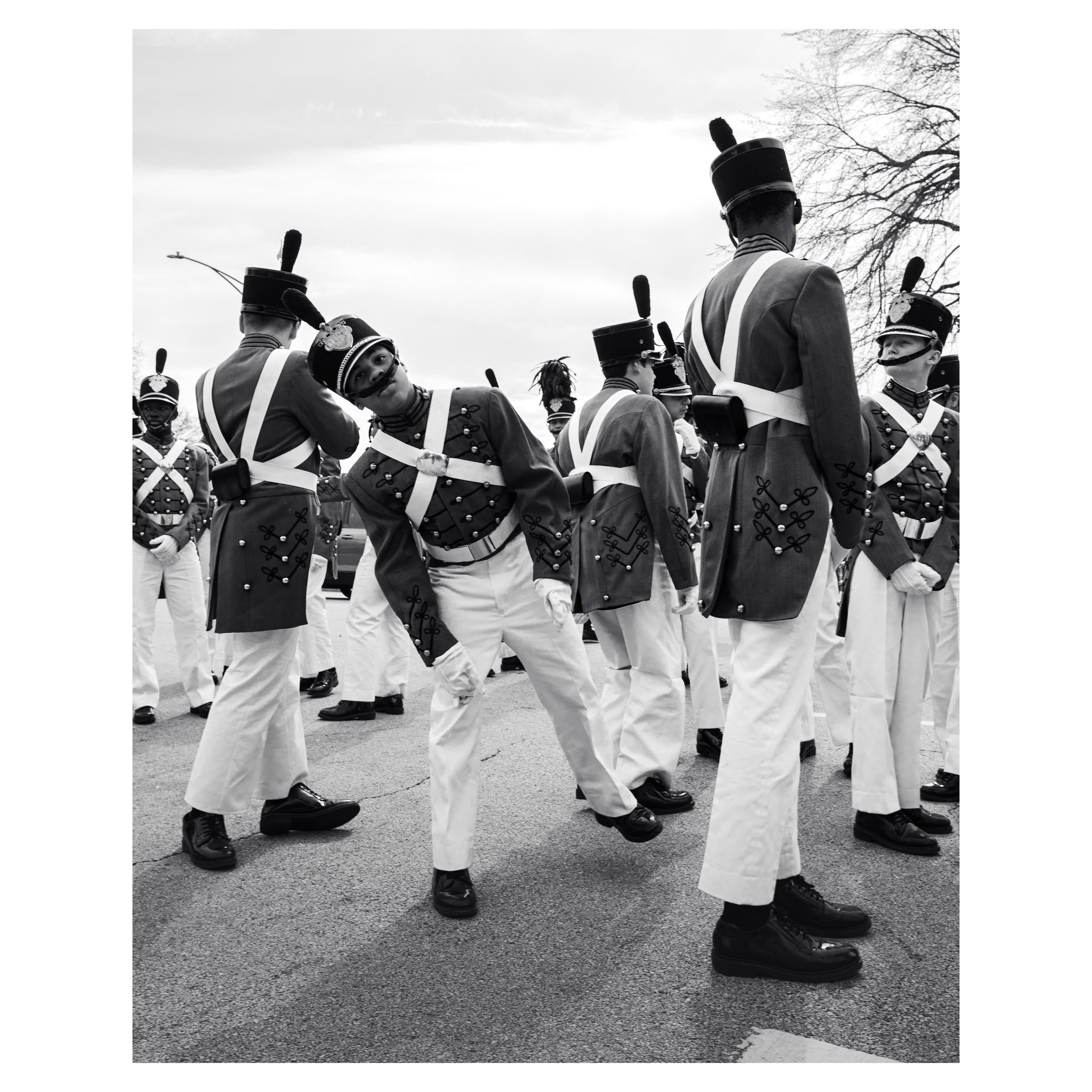 Street photo in Chicago  of young man in military school marching band making an toy like pose