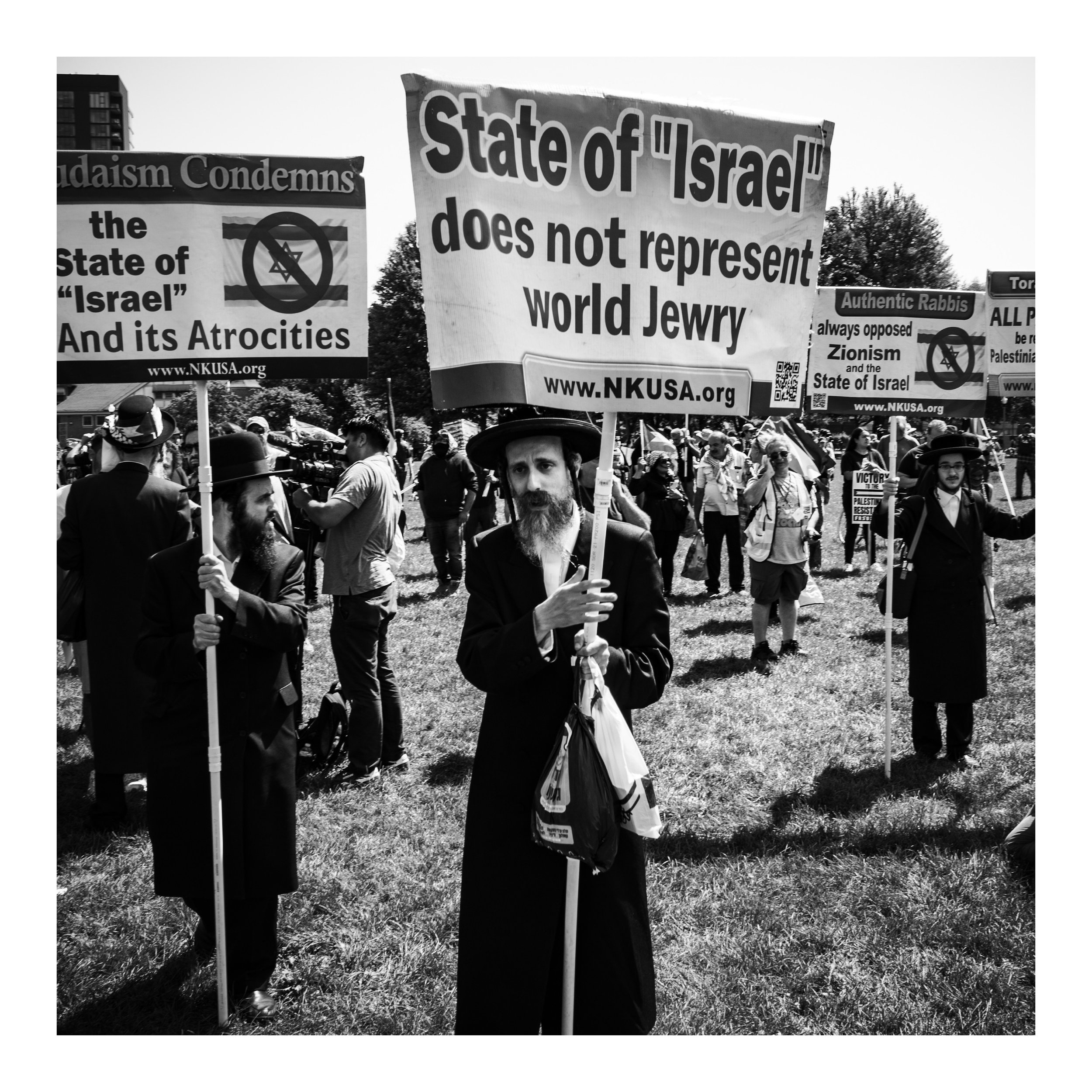 Black and white image of Jewish protestors holding signs condemning the occupation of Gaza