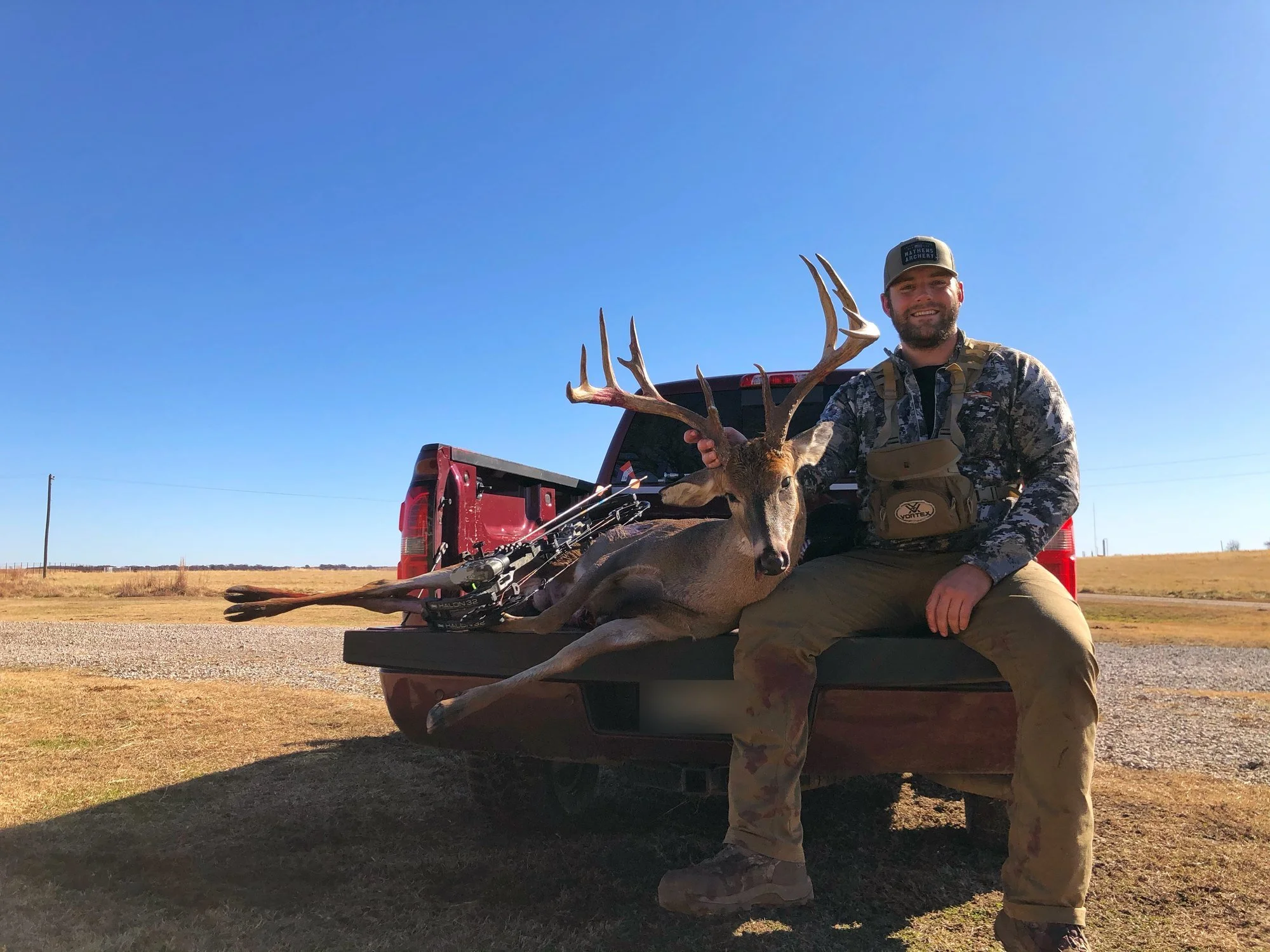 Hunter sitting on a truck tailgate with a mature whitetail buck
