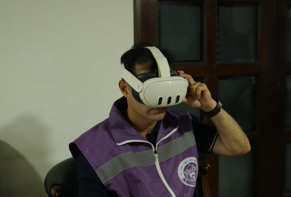 A person wears a VR headset and a purple vest with "100 Years Since Destruction" and "Let's
Wake Up" on an emblem.