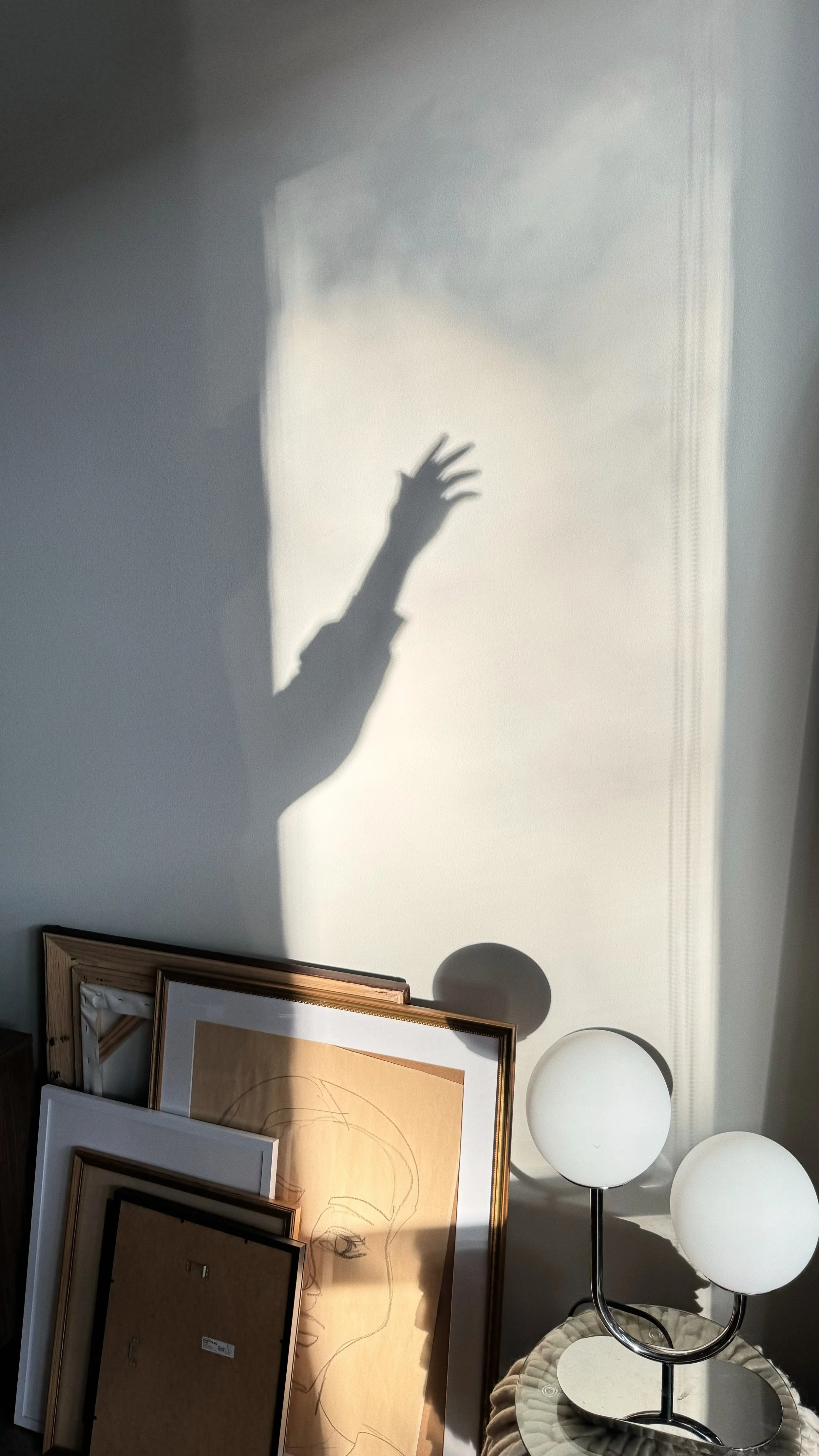Shadow of a woman's hand reaching upward on a white wall, representing the authentic self emerging during menopause and midlife transition