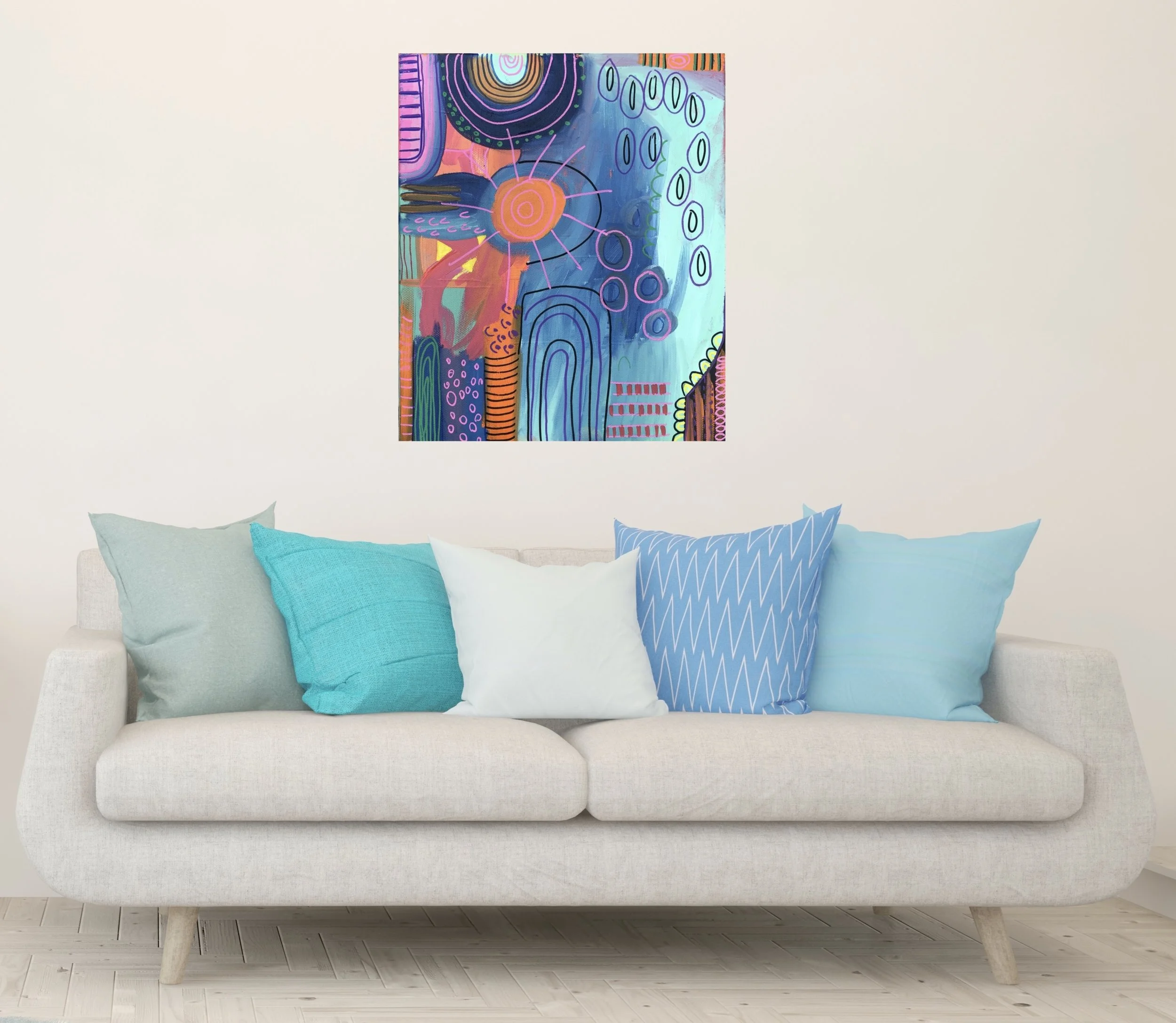 A white sofa with six blue and white pillows in front of a plain white wall. A colorful abstract painting hangs above the sofa.