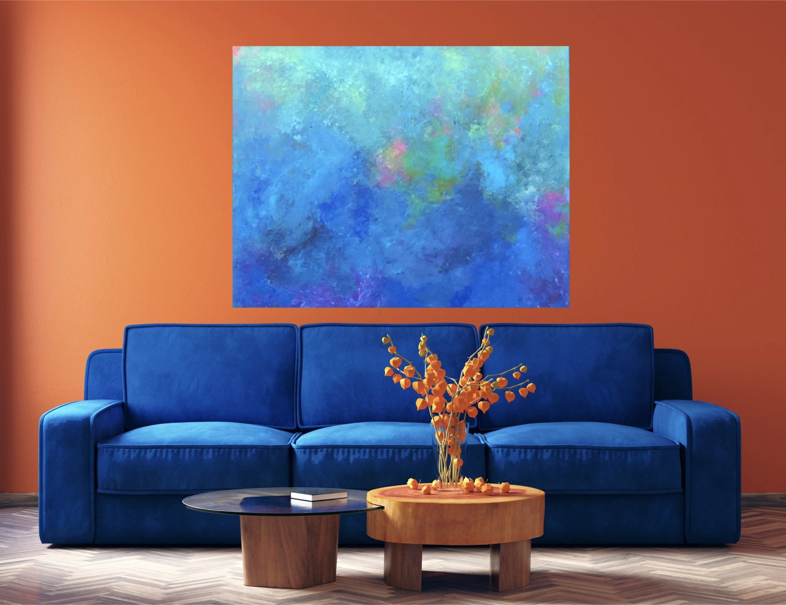 A living room with an orange wall, a large blue sofa with matching cushions, a round wooden coffee table with a floral arrangement, a black side table with a book, and an abstract blue and green painting hanging on the wall.