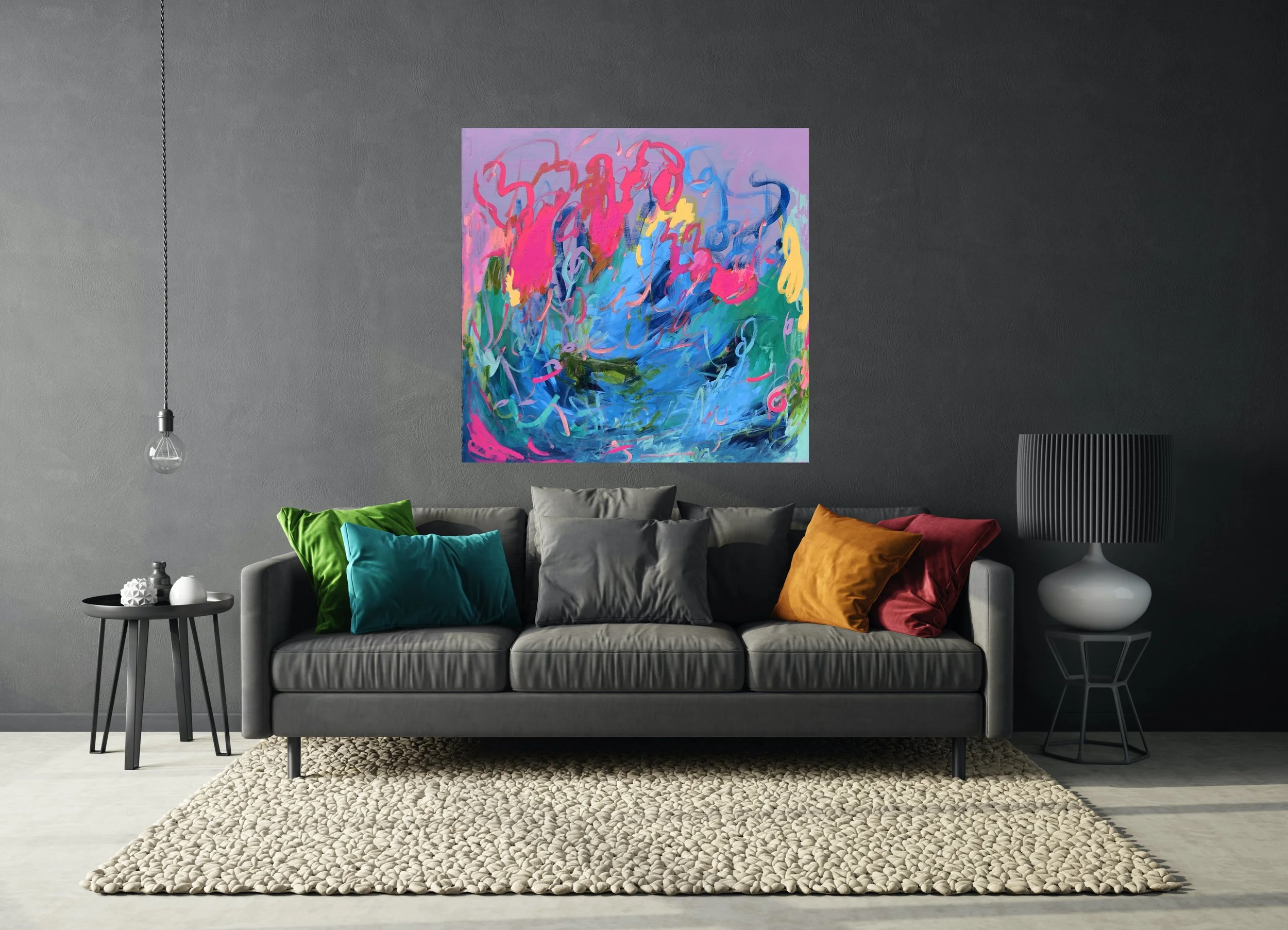 Living room with a dark gray sofa with multiple colorful pillows, a beige textured rug, a small black side table with vases, a black and white lamp, and a vibrant abstract painting on a gray wall.