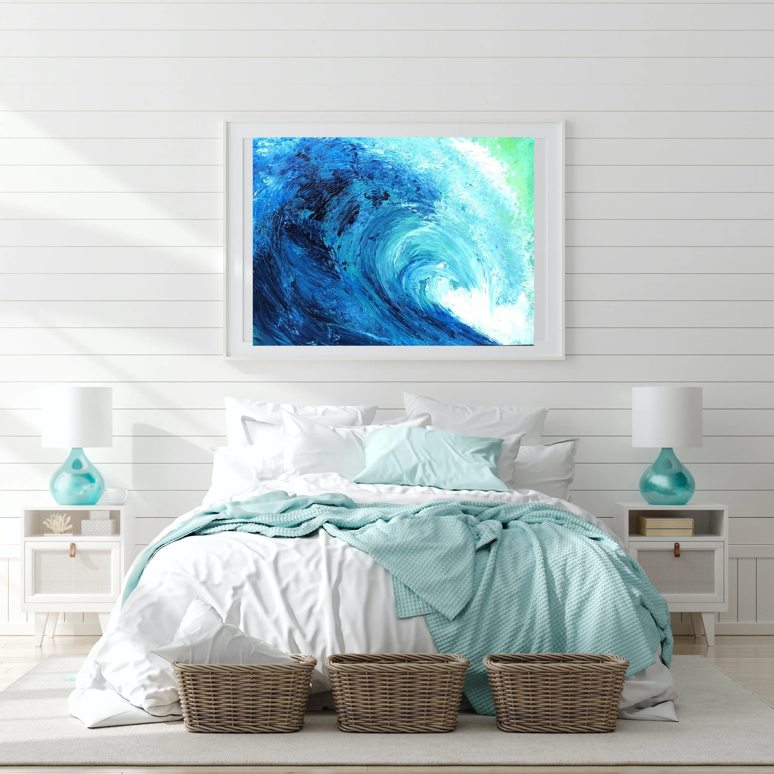 A bedroom with white shiplap walls, a bed with white bedding and a light blue blanket, two white nightstands with blue lamps, and a large framed painting of an ocean wave above the bed.
