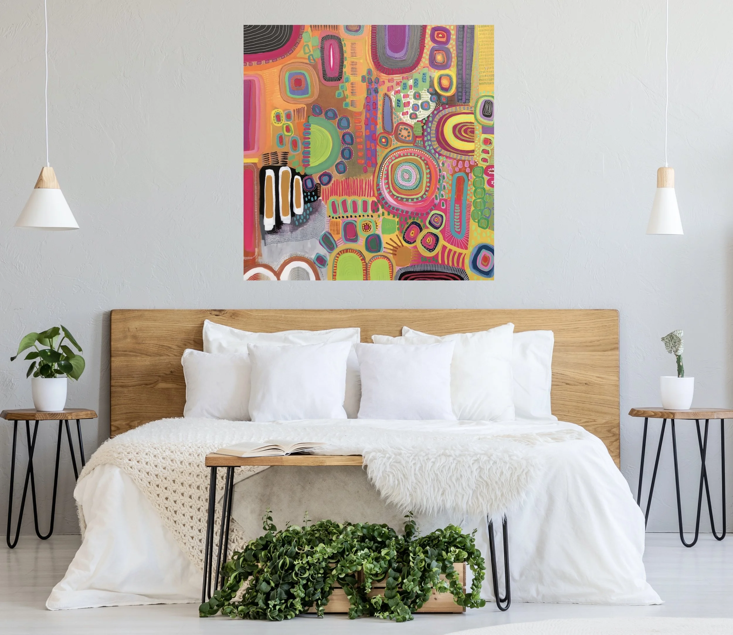Minimalist bedroom with a wooden bed frame and white bedding, flanked by two plant and flower arrangements on side tables; colorful abstract art on white wall