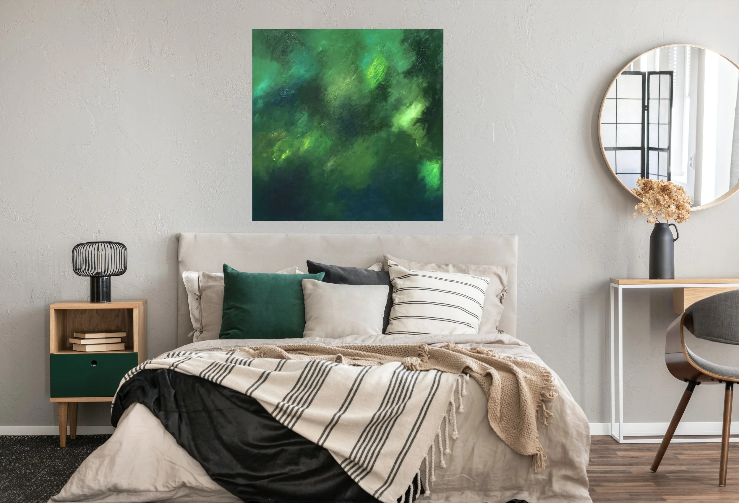 A modern bedroom with a bed, green, beige, and black pillows, a black and beige striped throw blanket, a side table with books and a black lamp, an abstract green painting on the wall, a black vase with dried flowers on a white desk, a large round mi