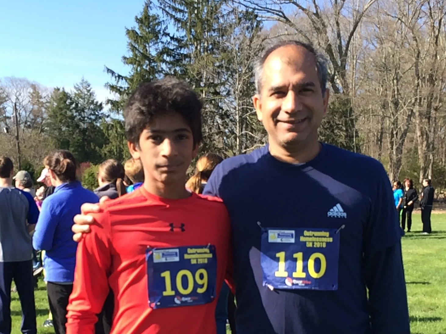 Father and son wearing athletic clothing with numbers pinned to shirts at run event