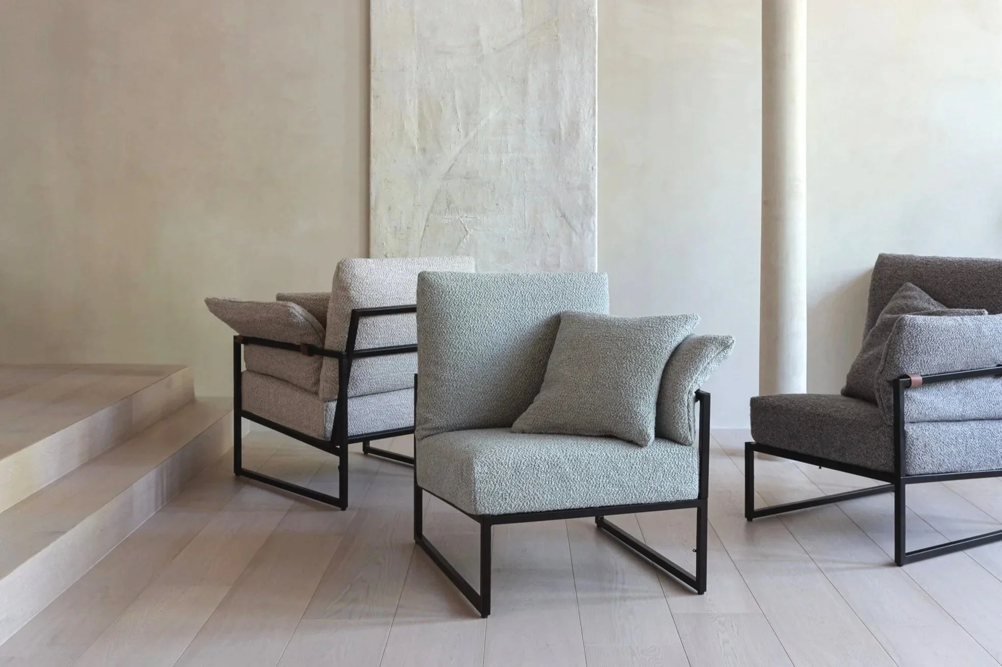 Ligne Pure Belgian multi-me sofa and rug - Modern chairs with textured fabric and black metal frames in a minimalist interior with light-colored walls and flooring.