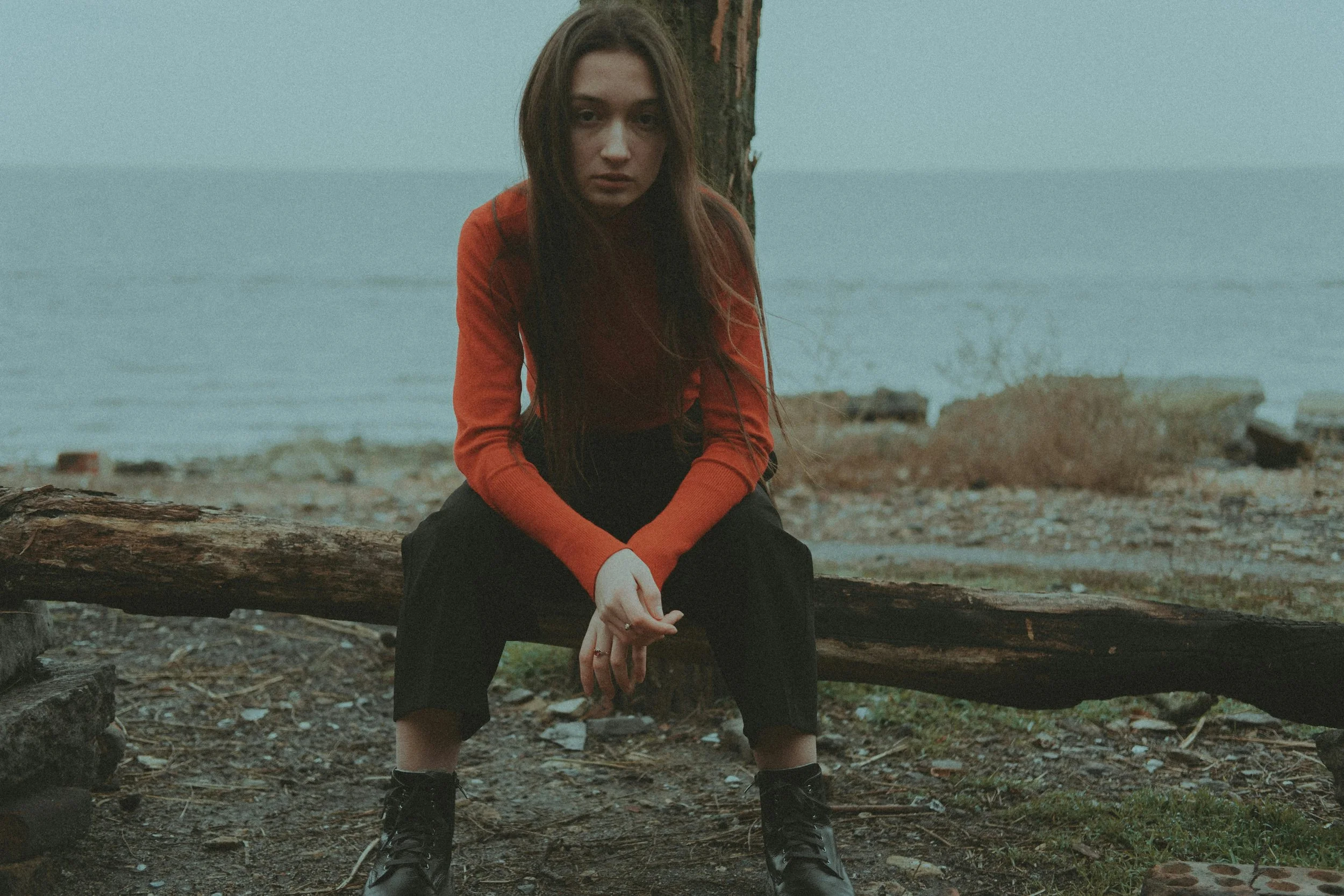 Woman seated outdoors by the shoreline, representing endometriosis fertility acupuncture care in North County San Diego