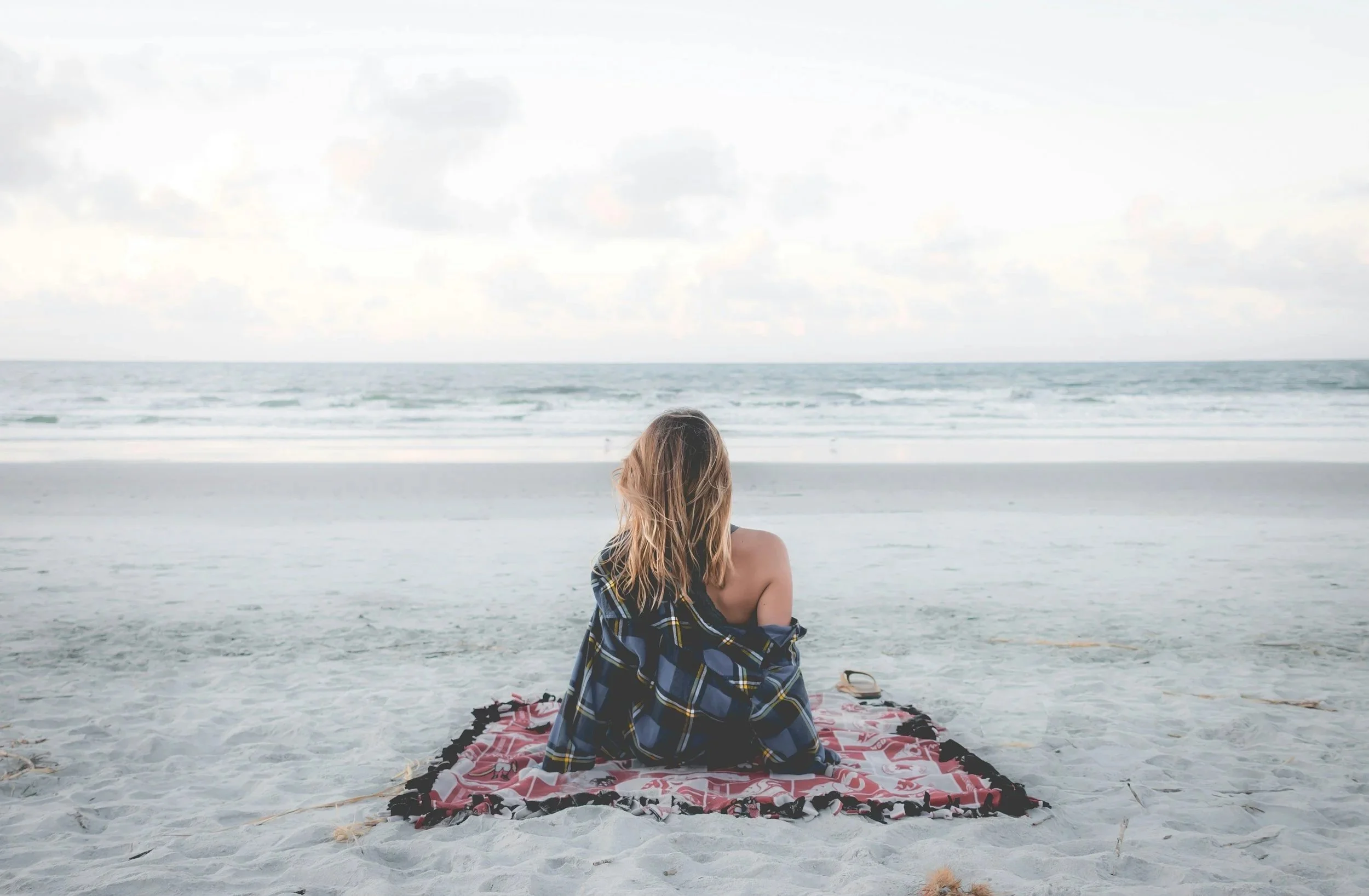 Woman sitting peacefully on the beach representing nervous system support and rest as part of fertility acupuncture at Fertile Earth Encinitas