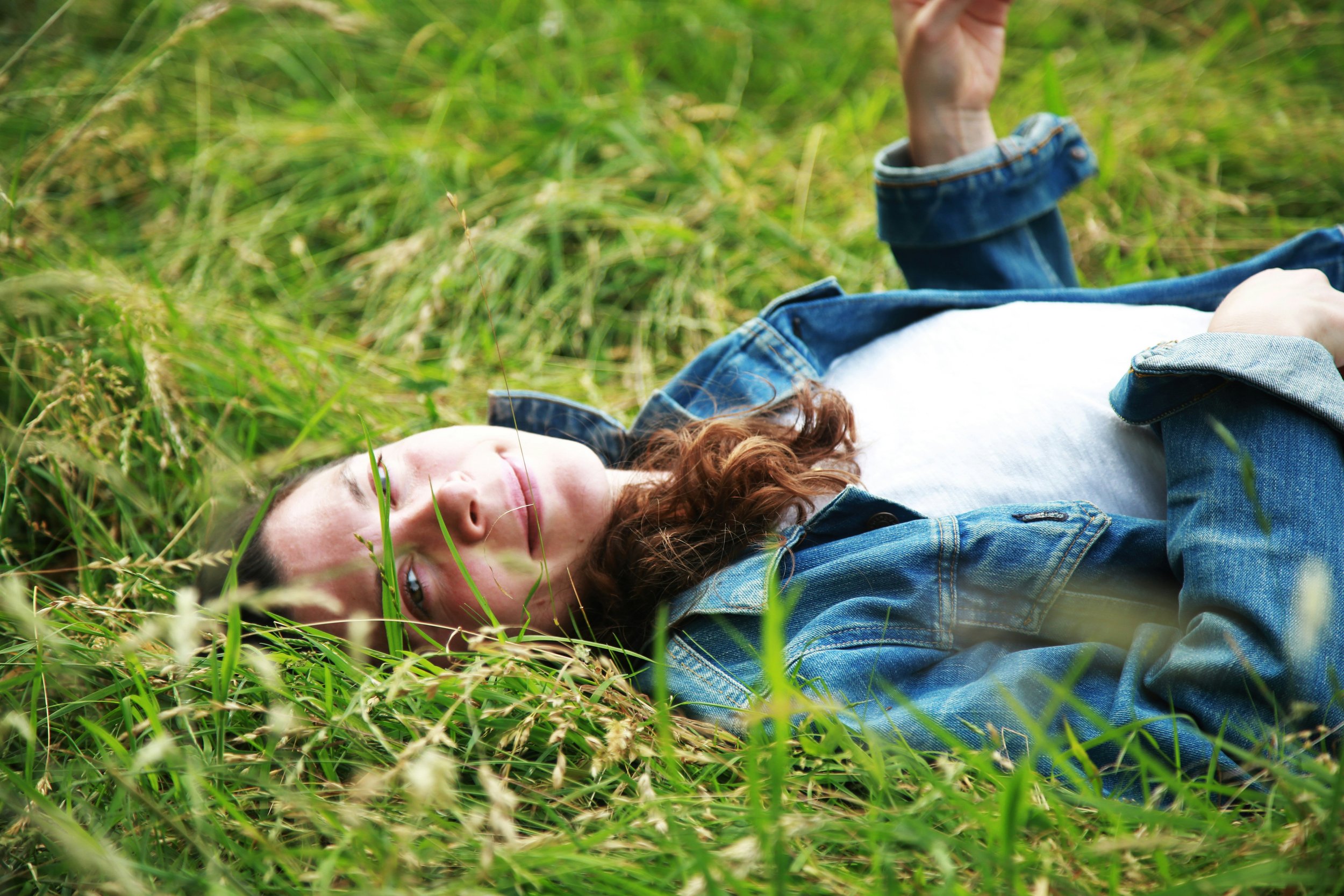 Woman lying in the grass representing consistent fertility care and the importance of the three-month treatment window at Fertile Earth