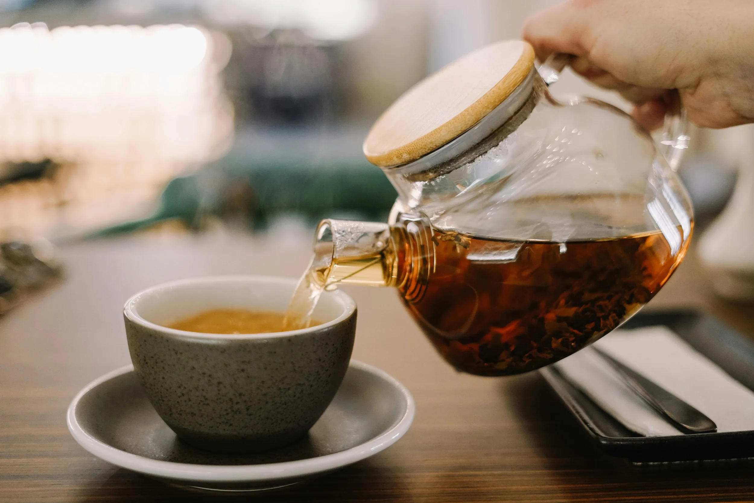 Herbal tea poured from a glass teapot representing daily herbal support for fertility at Fertile Earth in Encinitas