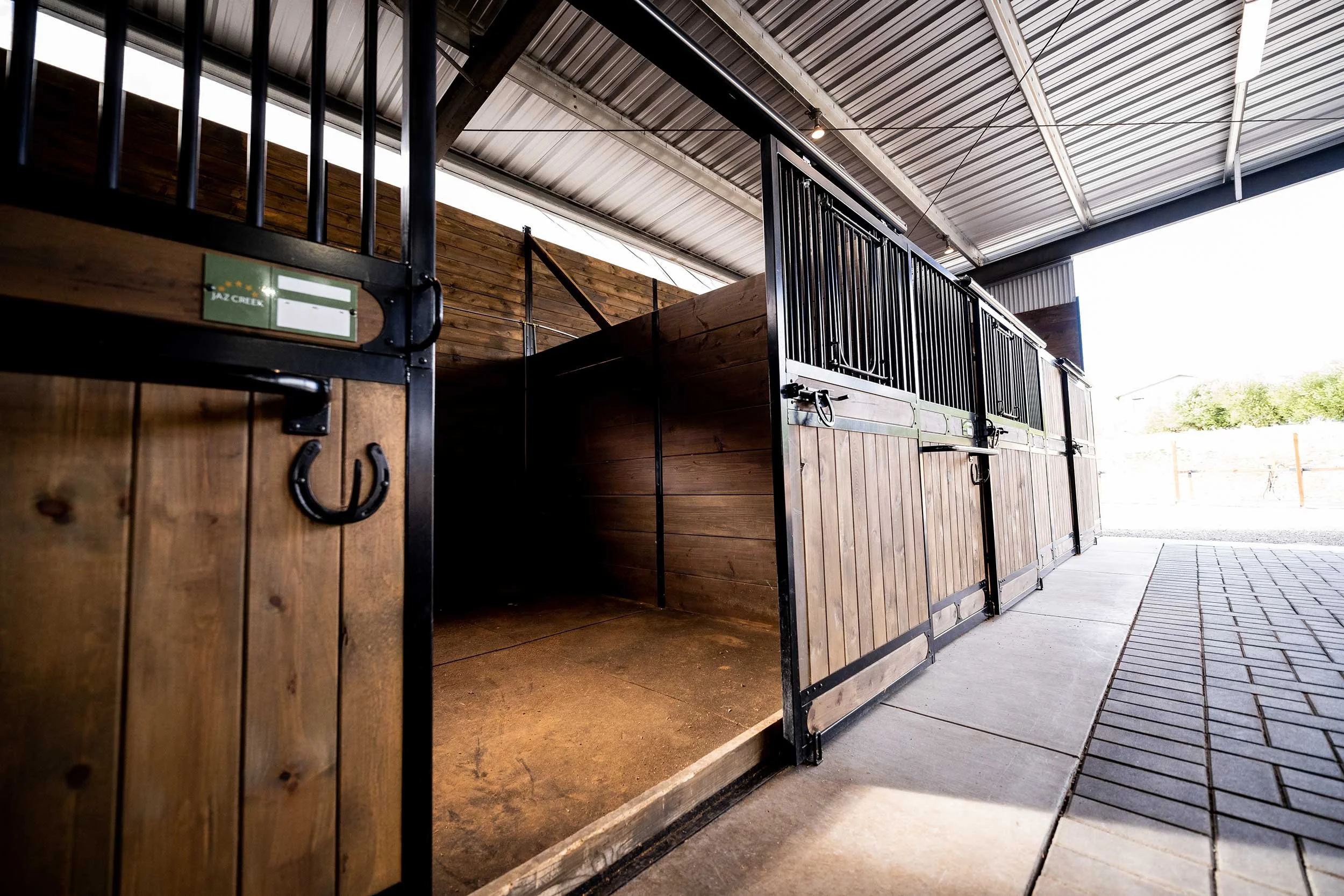An open stall door with horseshoe hook and hardware
