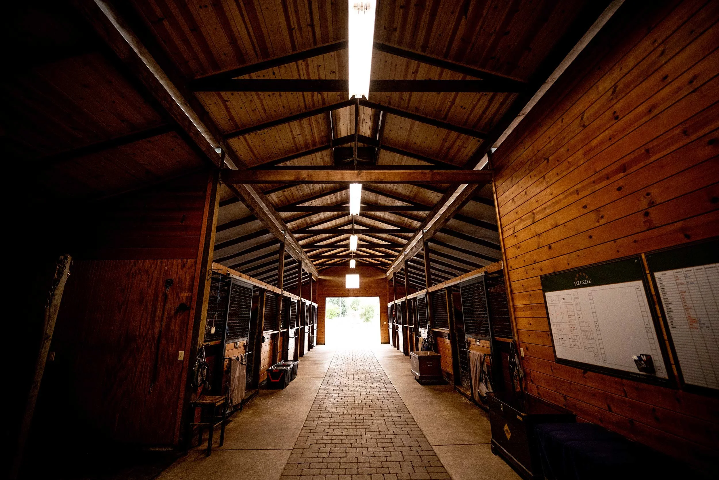Wooden paneled barn aisle with stalls on either side