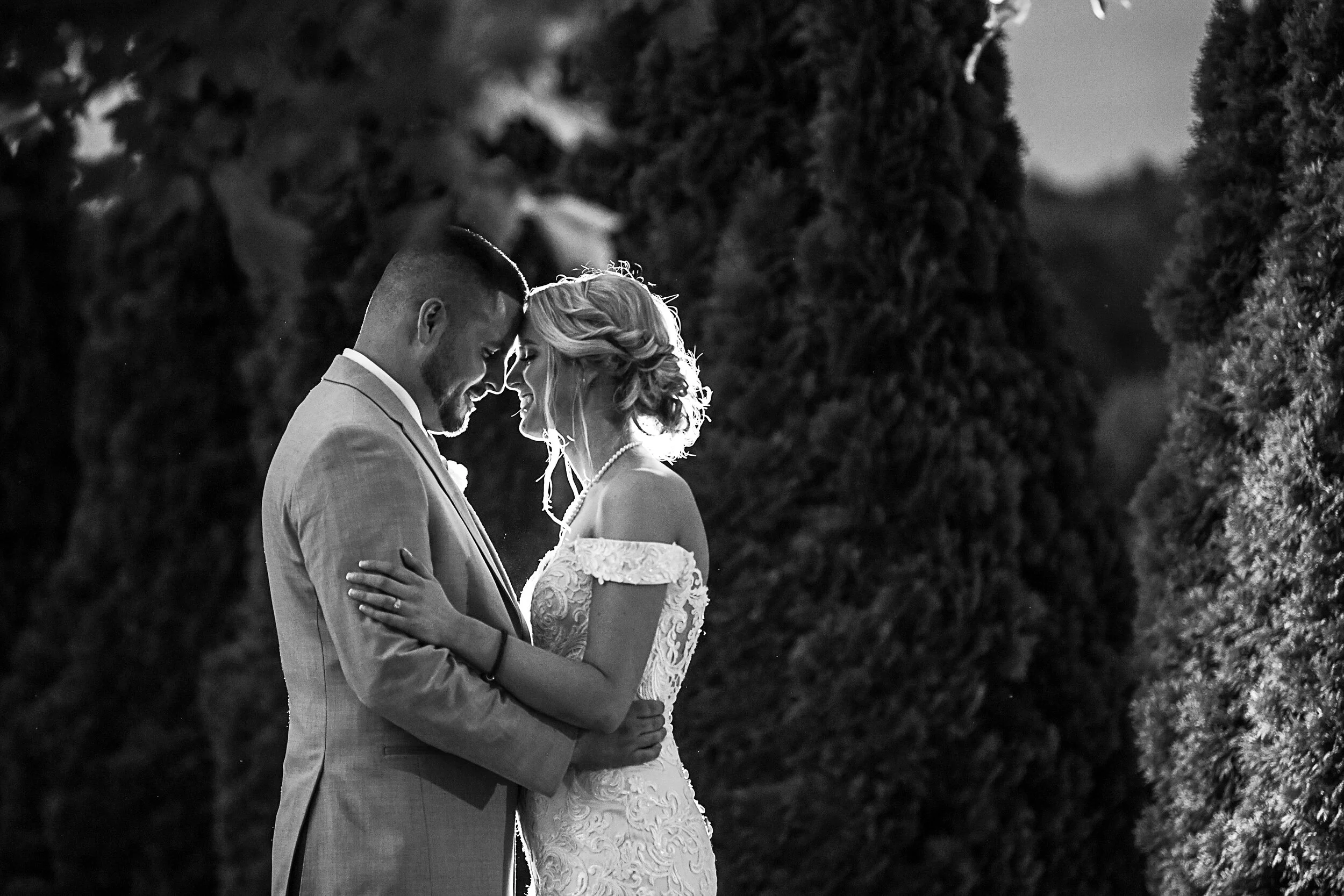 Bride and groom in an intimate embrace outdoors, black and white photo.