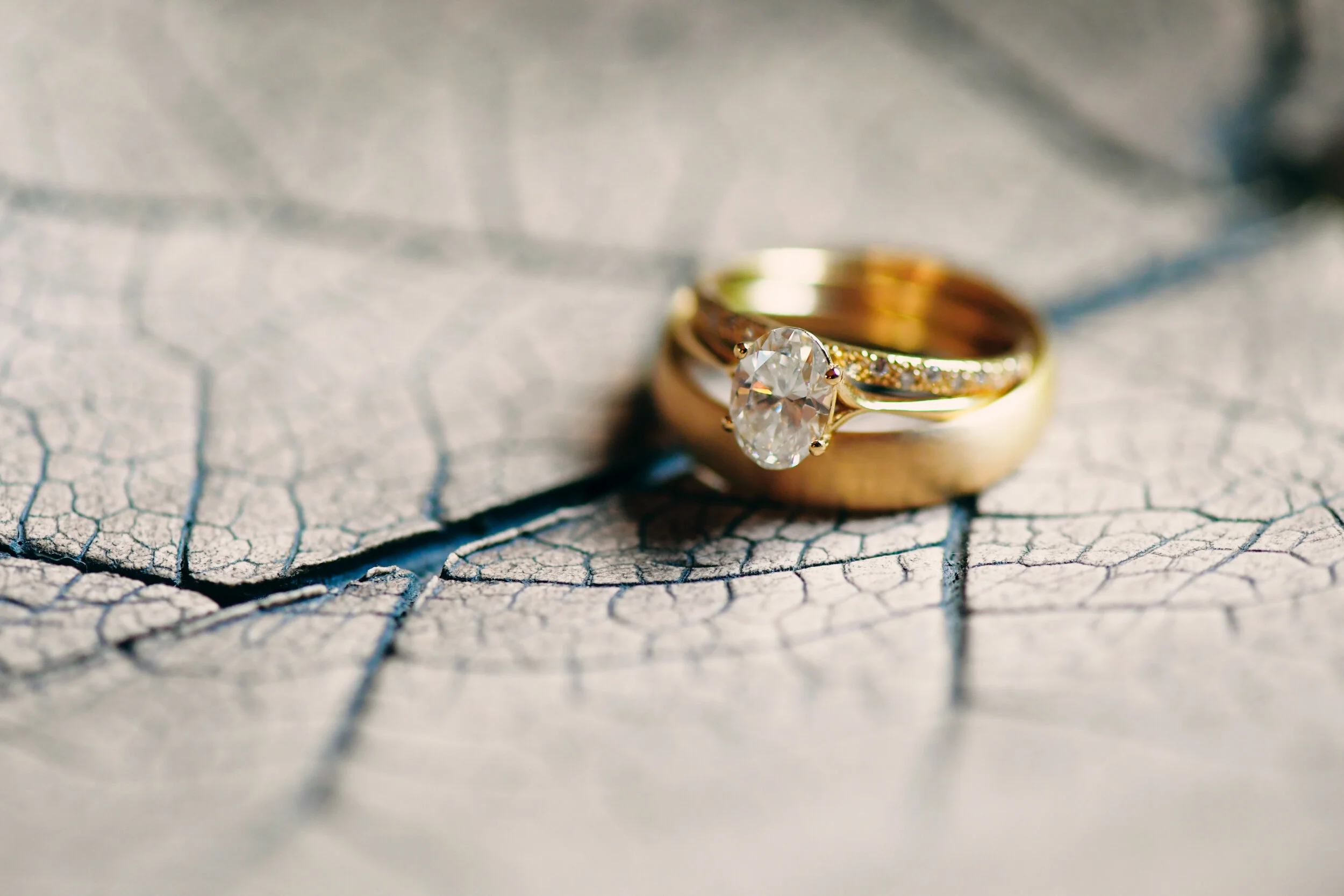 Gold ring with a large diamond on a textured leaf background.