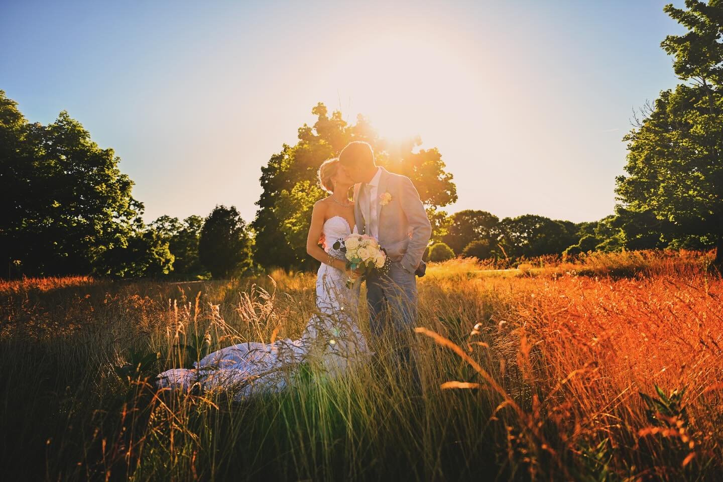Bride and groom kissing in a sunlit field