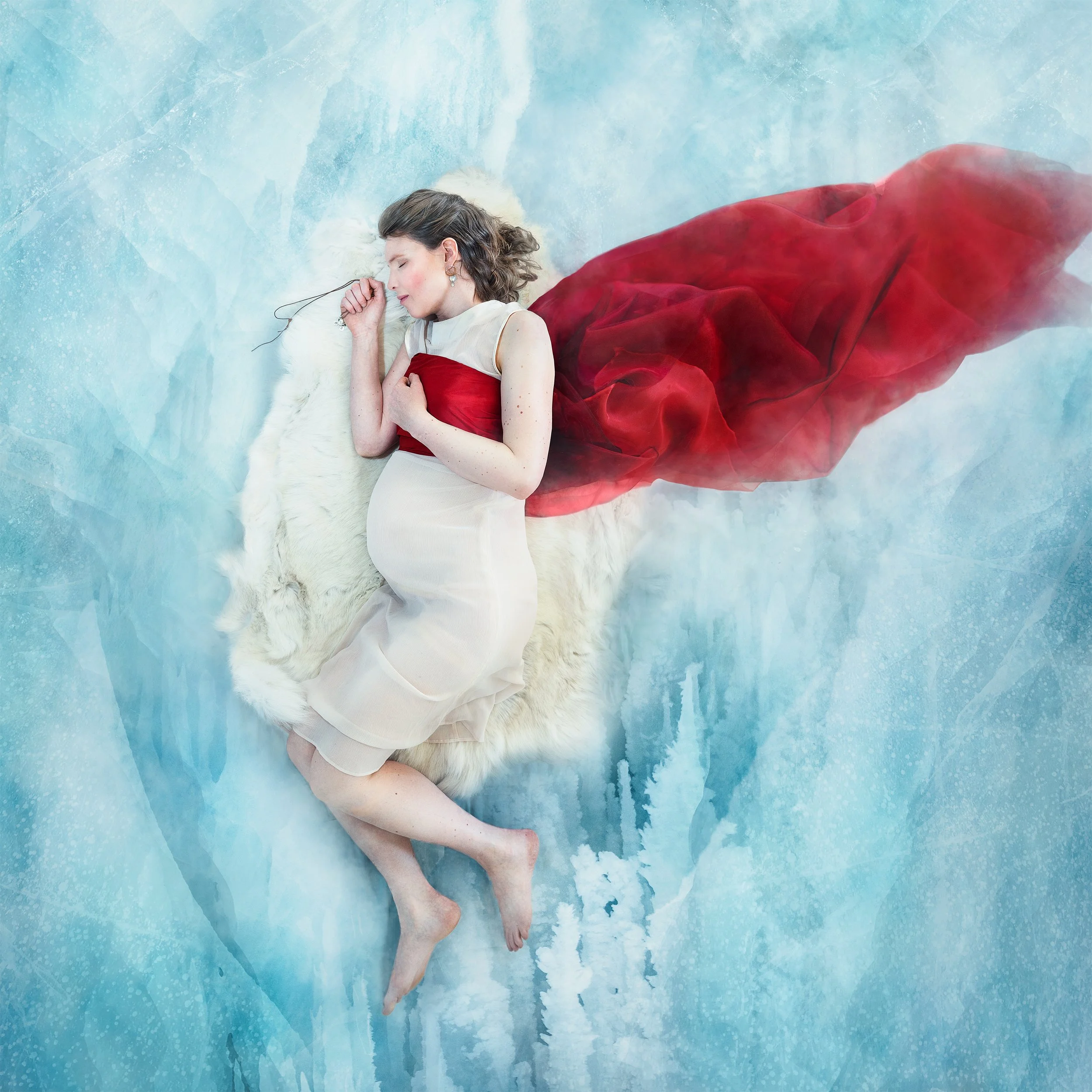 Mirja Palo, a pregnant woman in a white dress, lying on a white reindeer hide on ice. photographed by Lisa-Love Bäckman