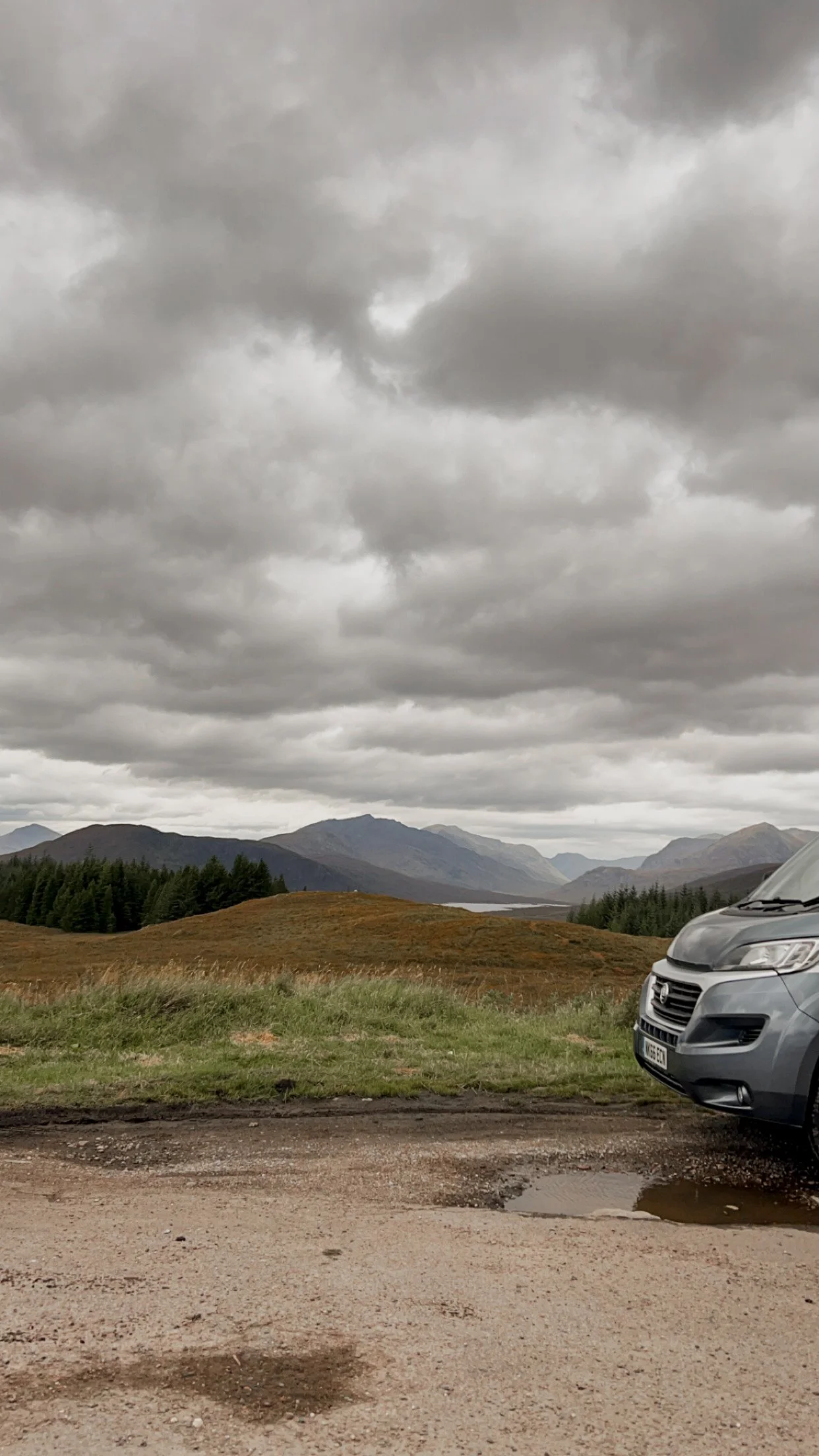 front of a van in front of mountains in scotland