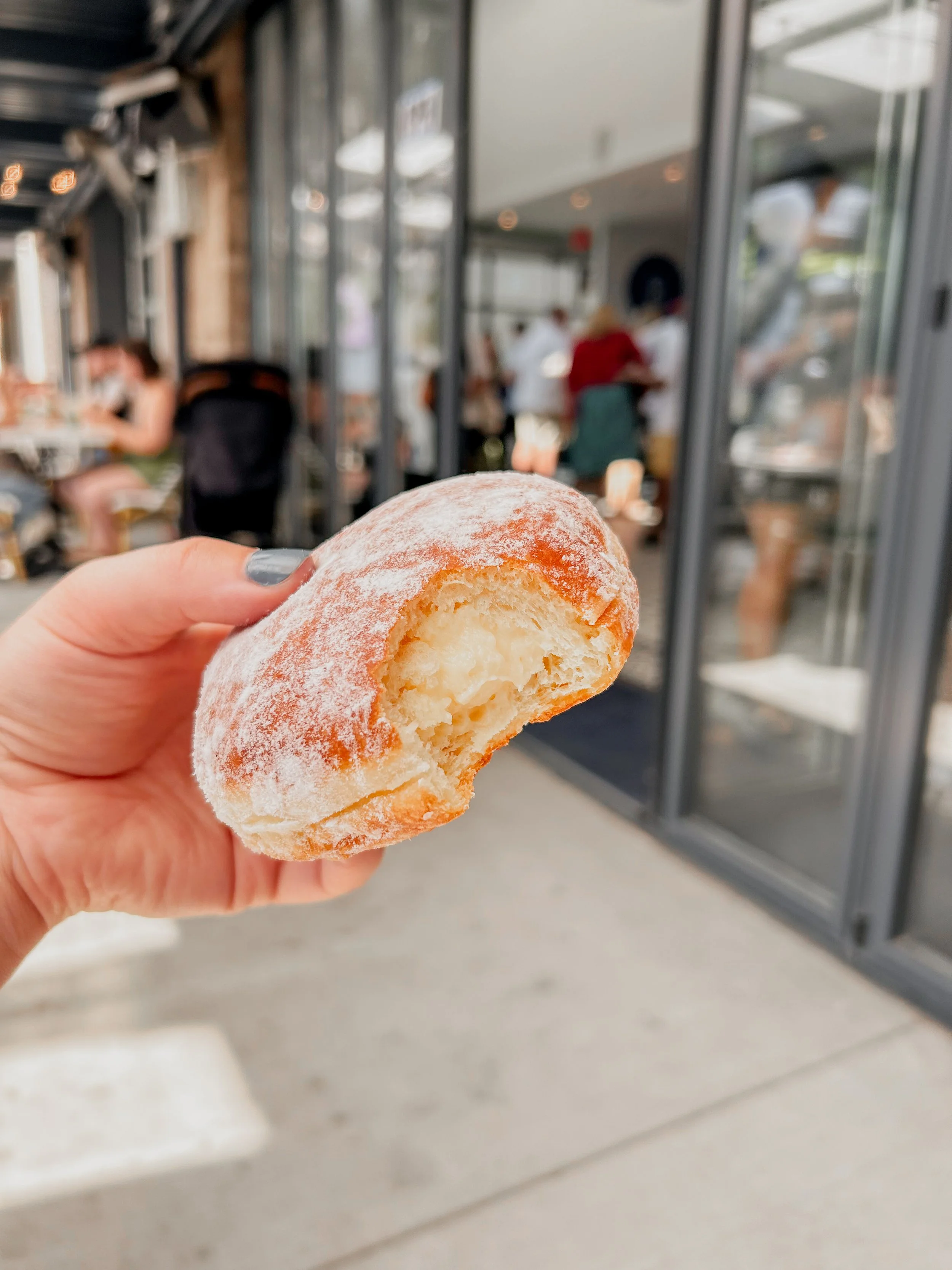 a filled donut from paris baguette being held by someone in the middle of the frame