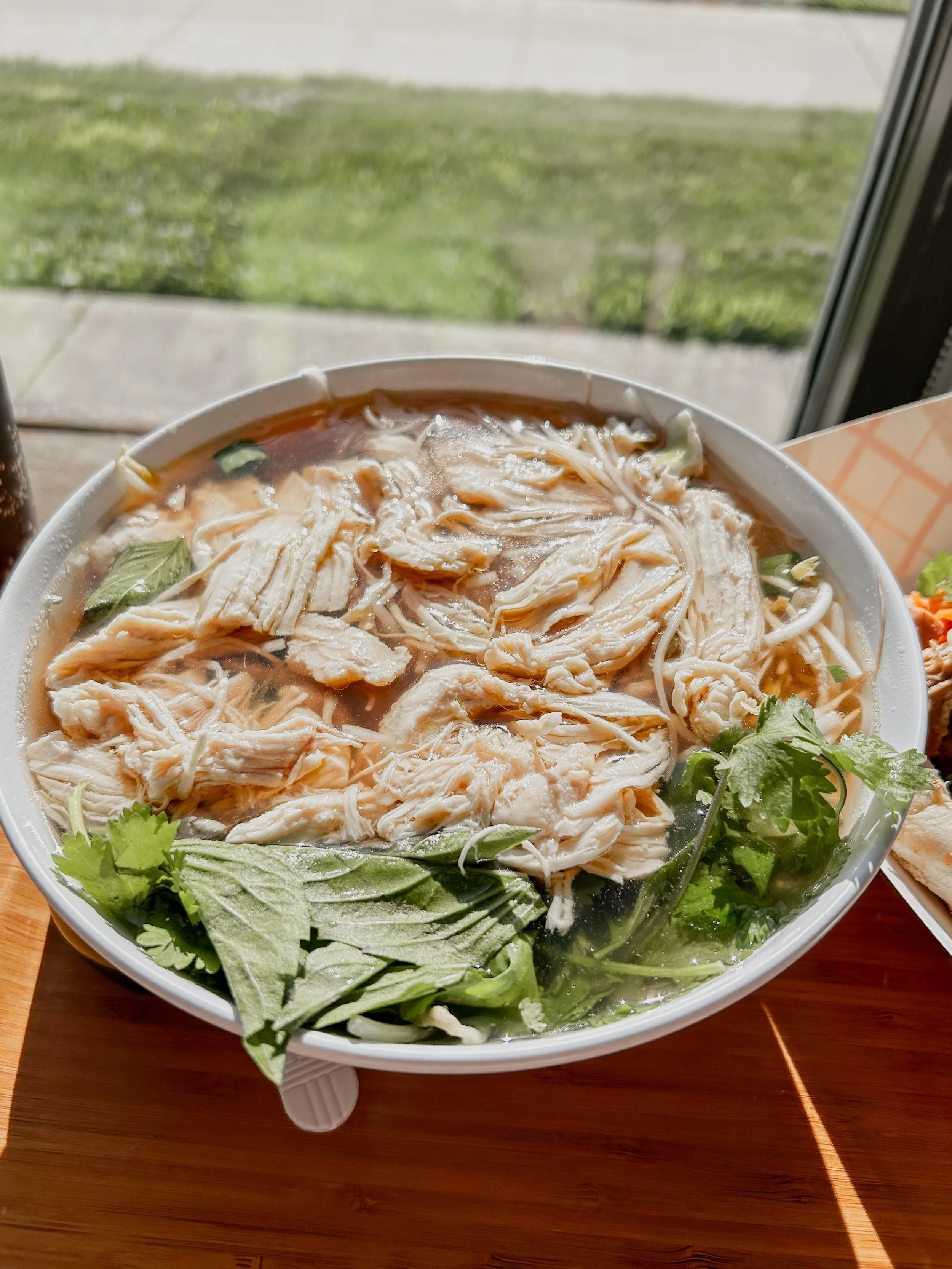 bowl of pho in front of a window