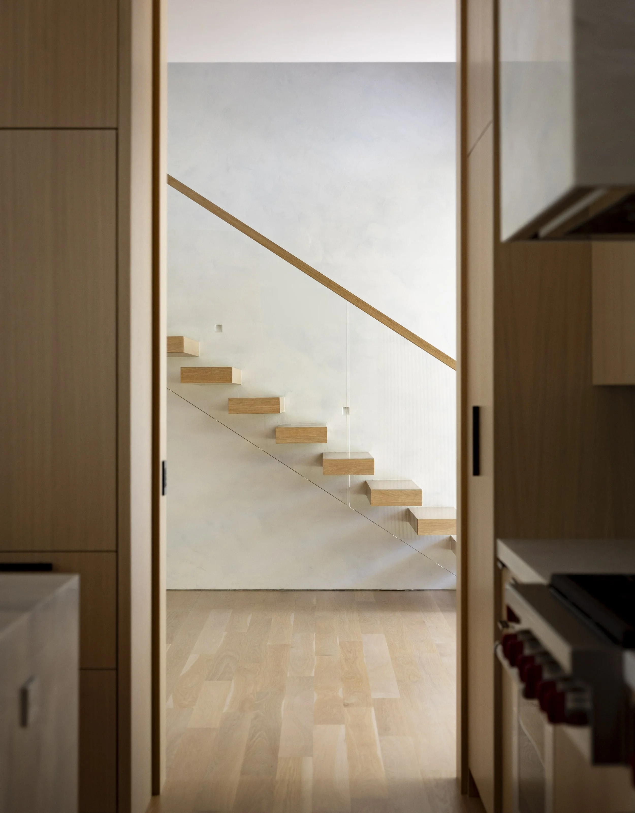 View of a modern staircase through a doorway, with wooden steps and minimal scenery.