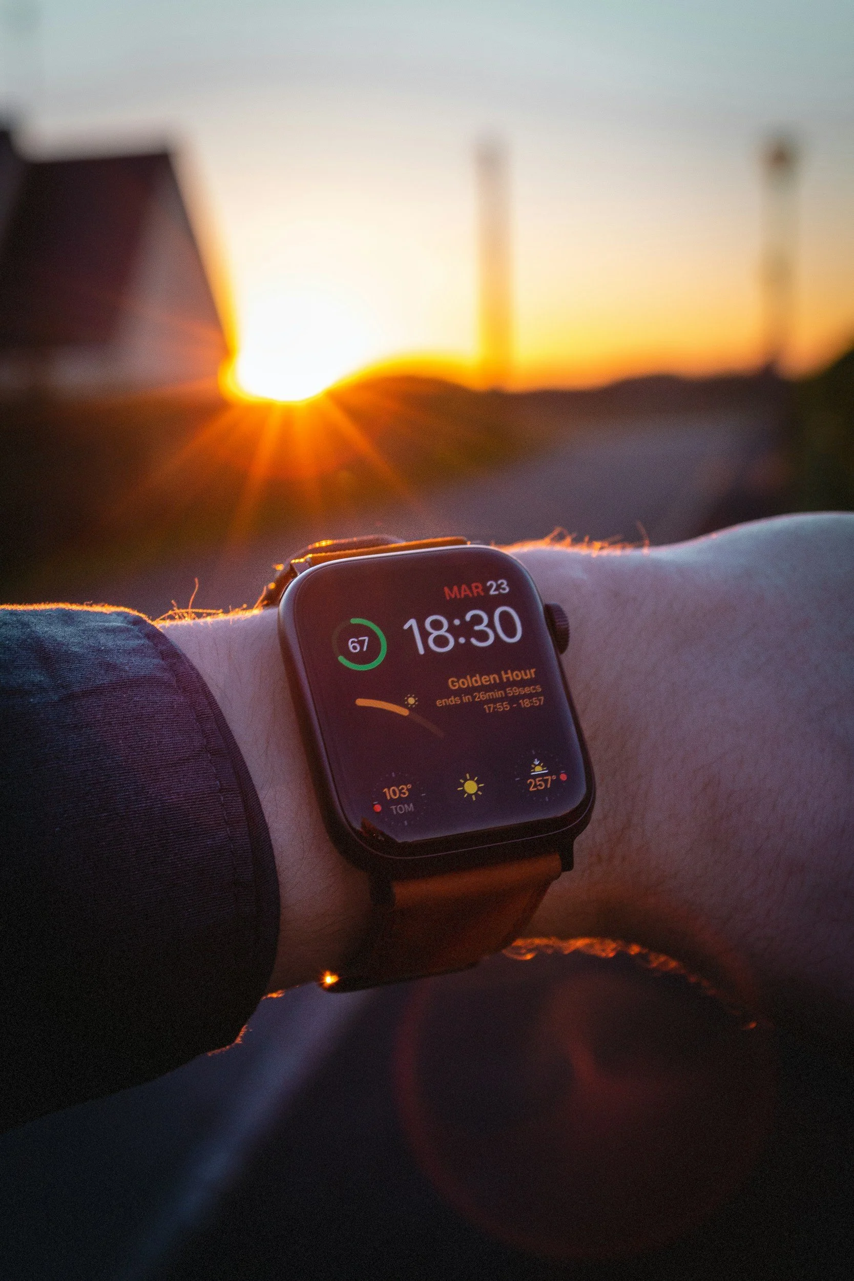 A smartwatch showing the time 6:30 PM, with a sunset background.