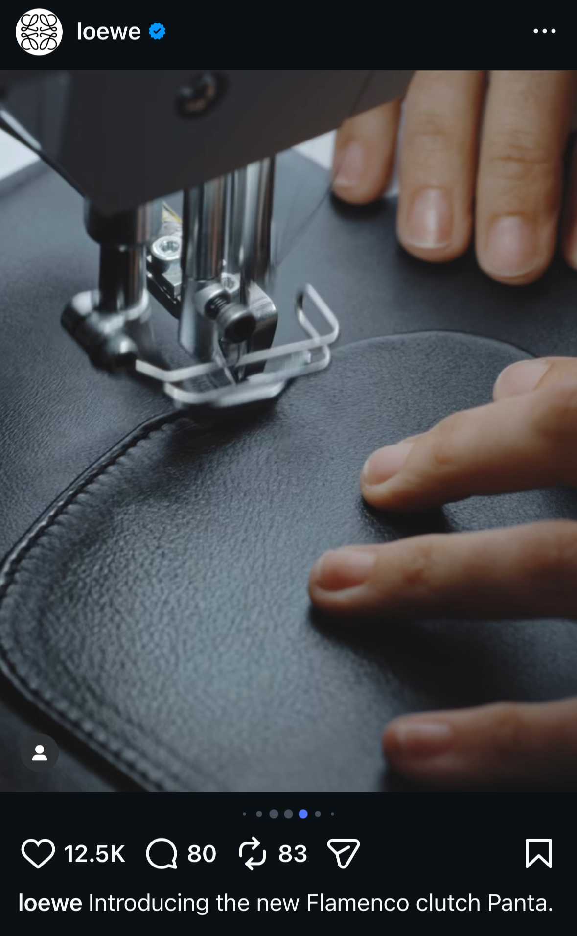 Close-up of hands guiding black leather under an industrial sewing machine, stitching the edge of a Loewe Flamenco clutch during handcrafted production.