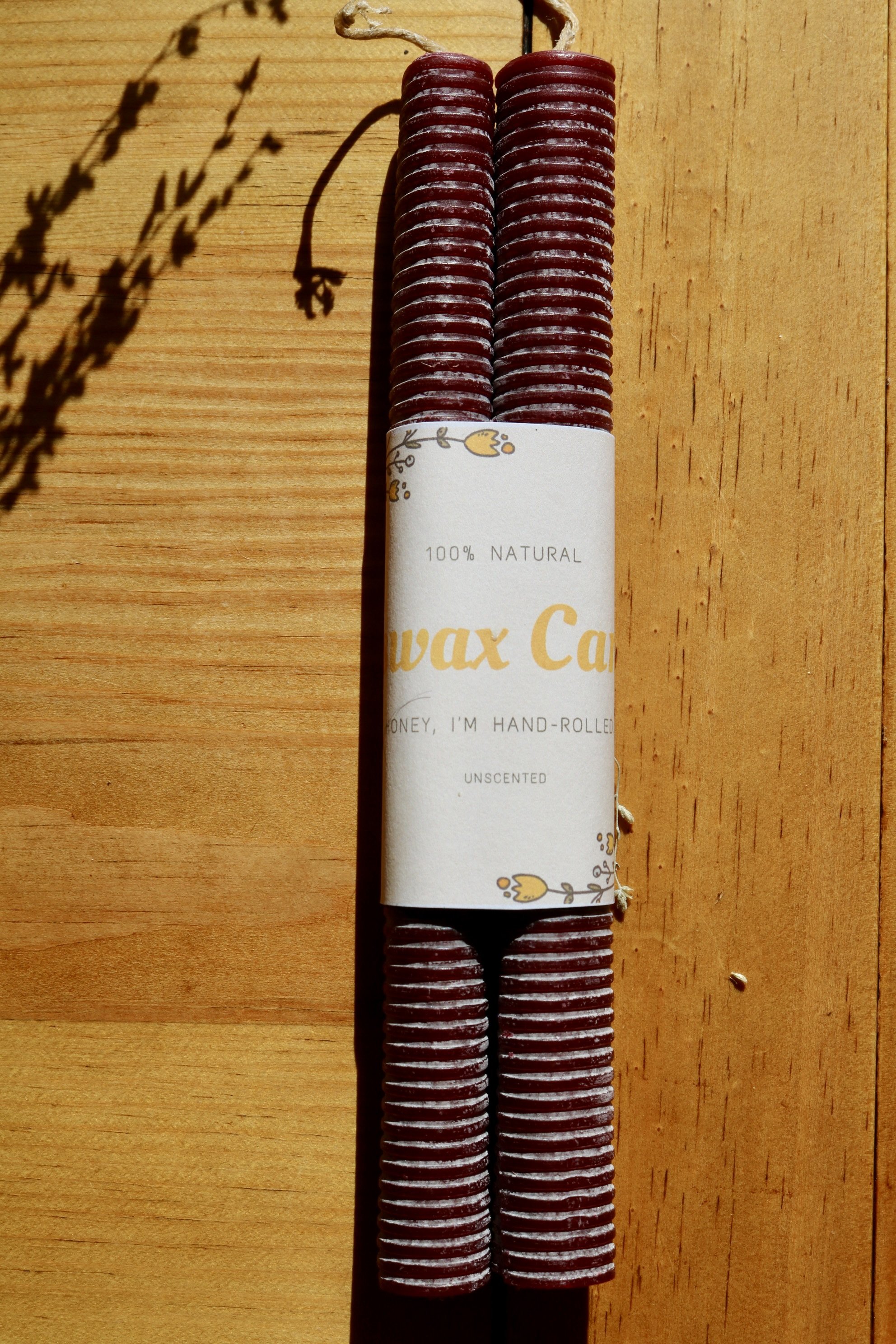 Cranberry colored hand-rolled corrugated beeswax candle