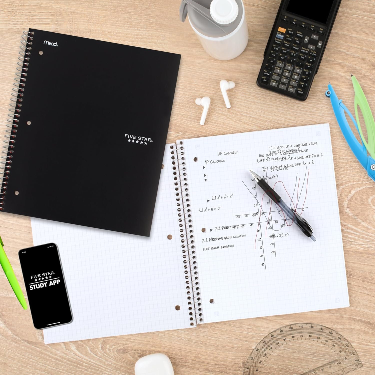 Five Star graph-ruled spiral notebook open to handwritten calculus notes and graphs, surrounded by school supplies, and a scientific calculator.