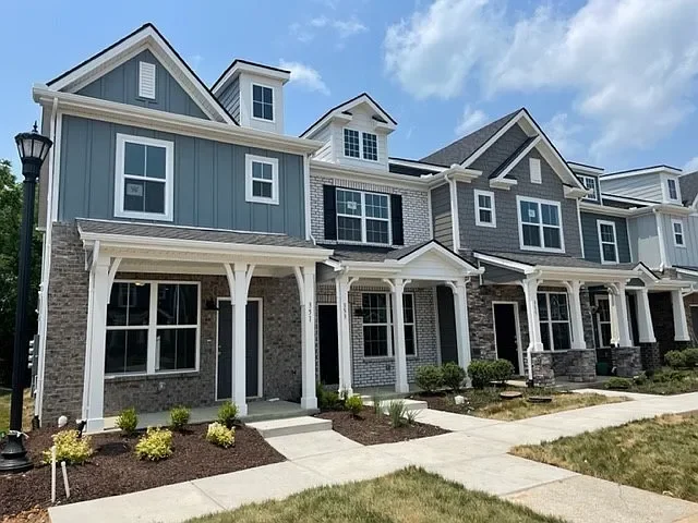 Row of modern Nashville townhomes featuring mixed siding, front porches, and fresh landscaping..webp