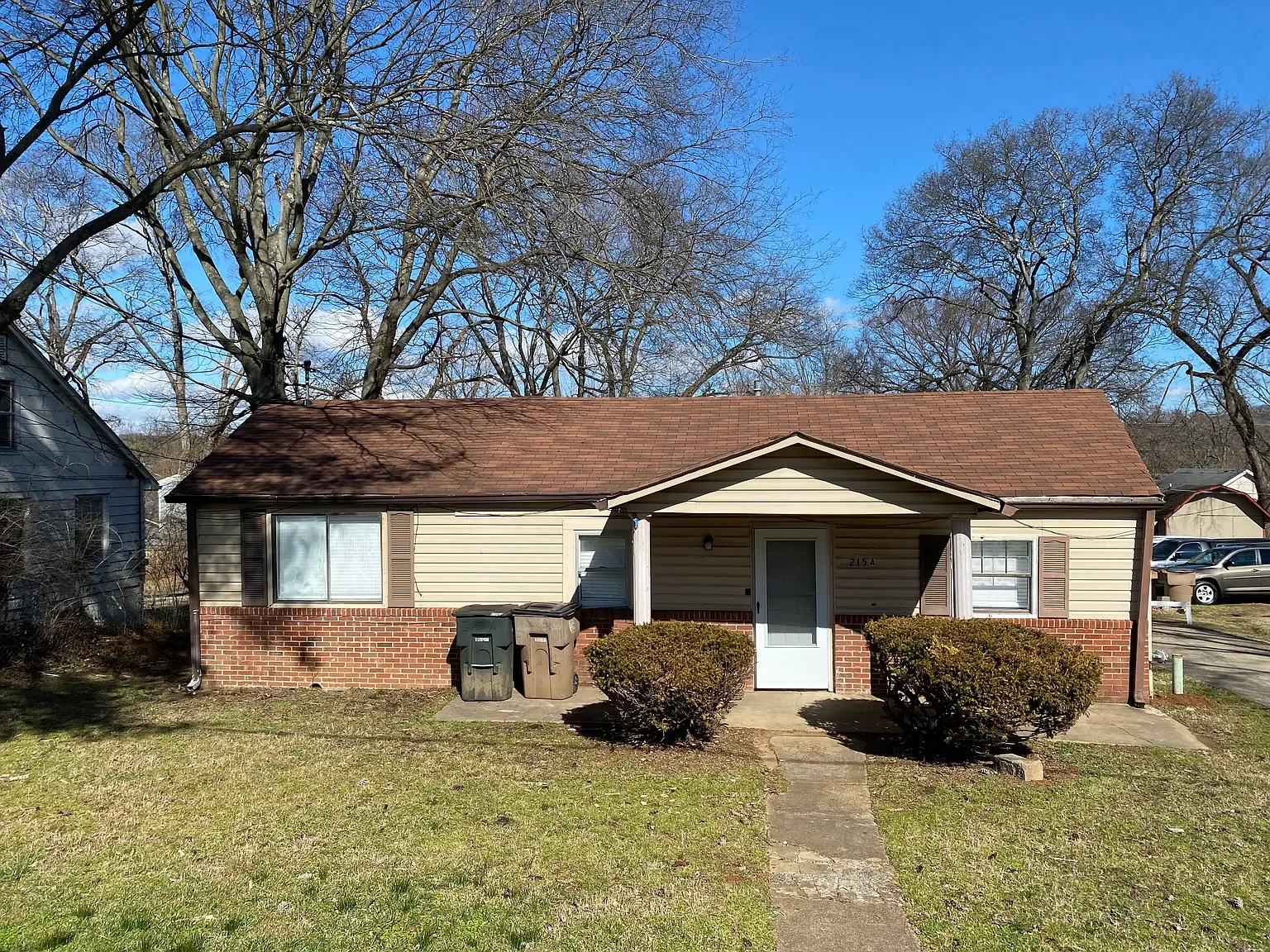 Single-story Nashville ranch-style home with brick and siding exterior, brown roof, and shaded front yard..webp