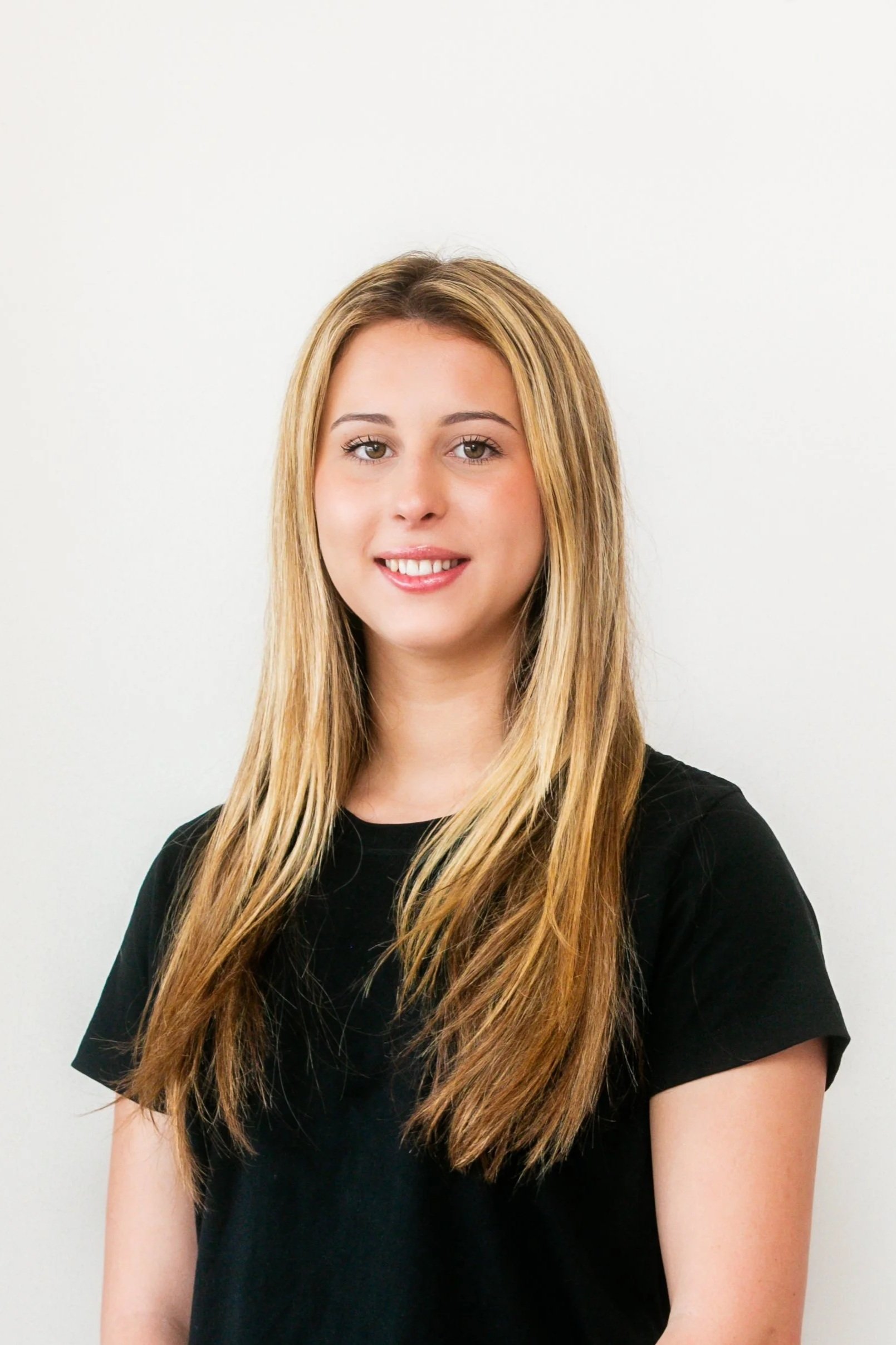 A young woman with blond hair, smiling in front of a lady holding up manicured hands
