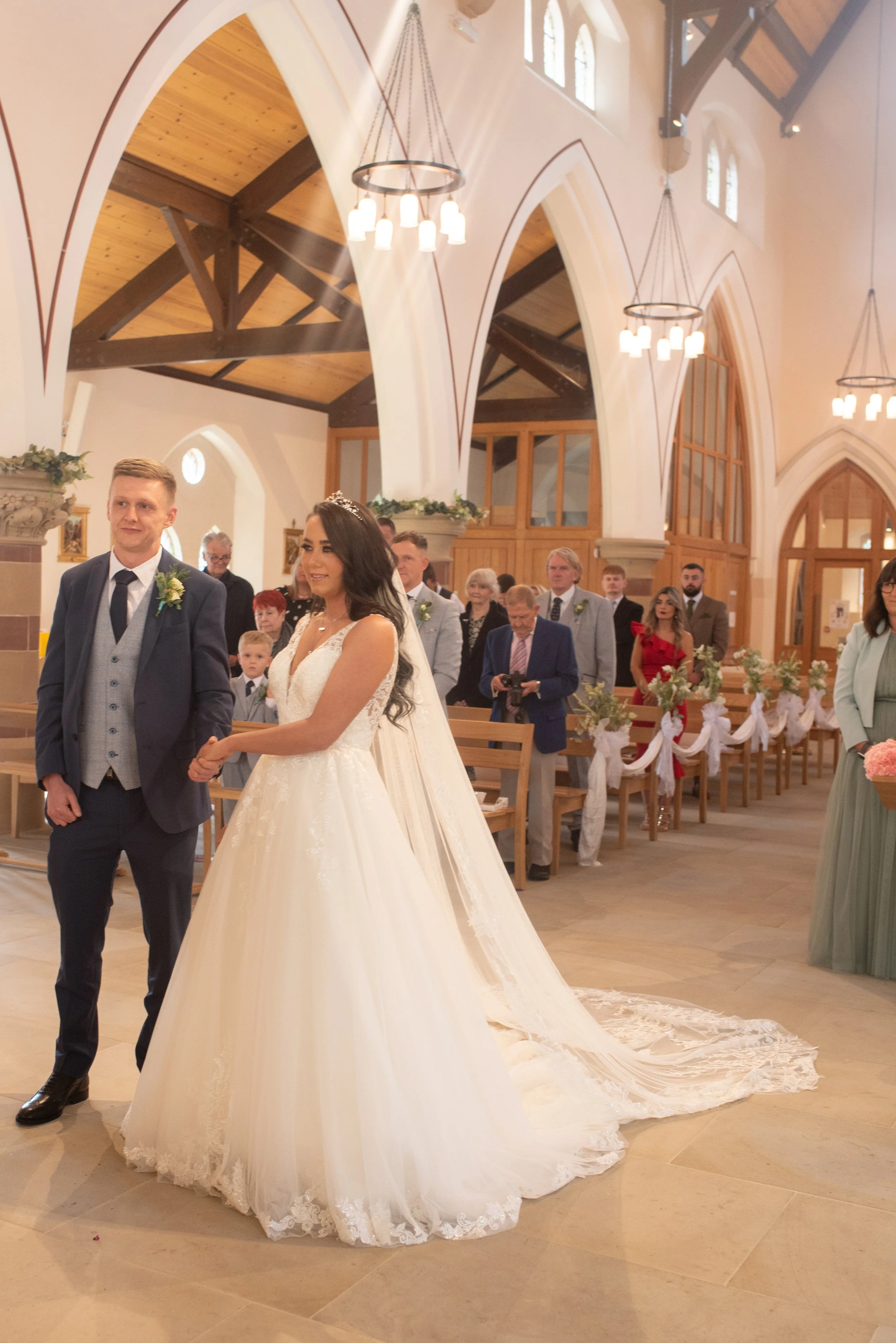 A bride and groom holding hands during their wedding ceremony inside a church.