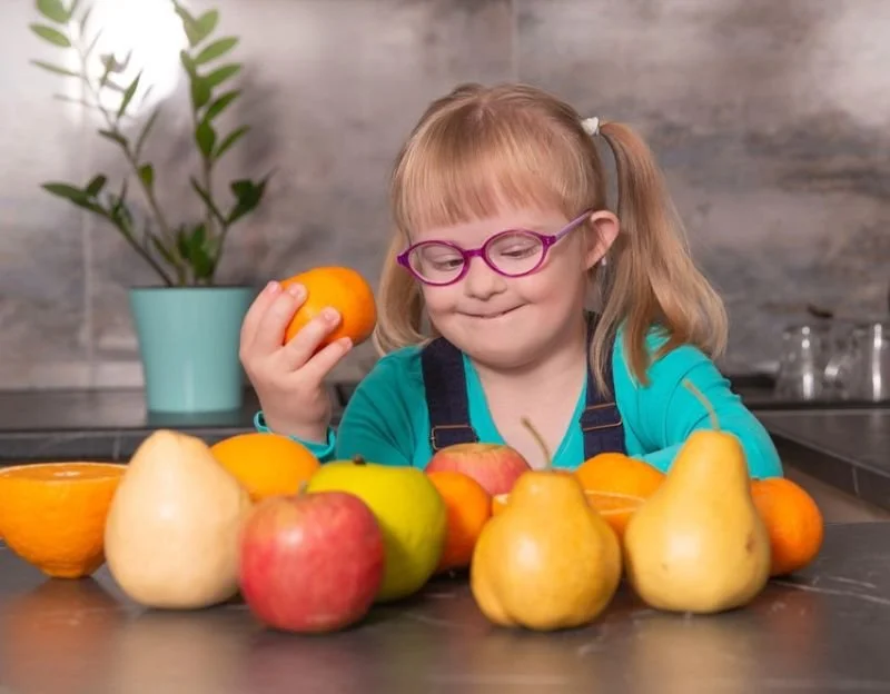 Child with Down syndrome choosing from different fruits.