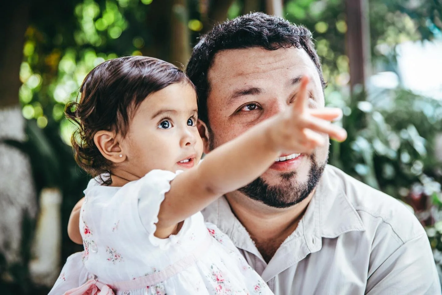 Father holding a toddler who points ahead.