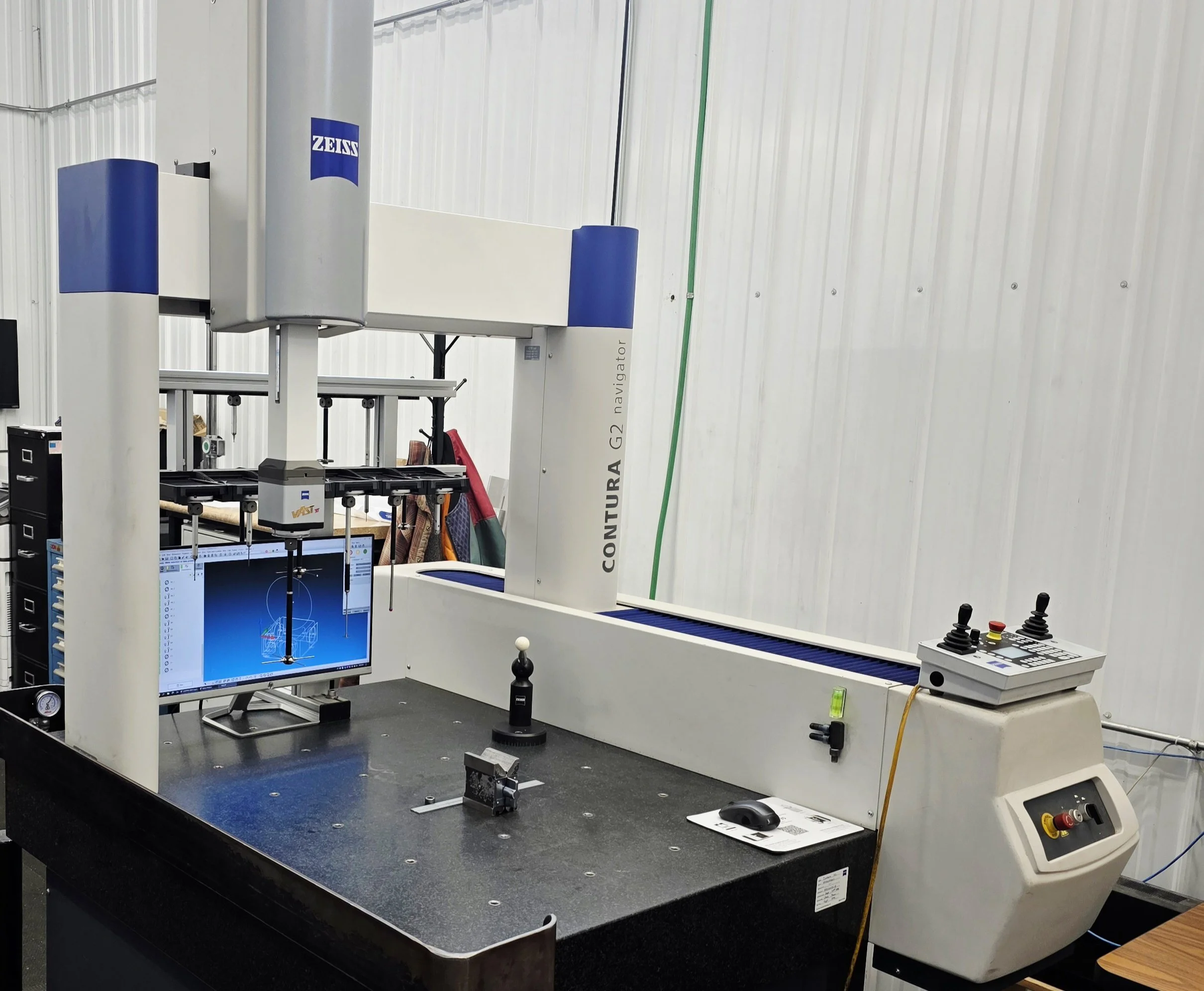 A Coordinate Measuring Machine (CMM) labeled 'CONTURA G2 navigator' with a computer monitor and control panel in an industrial setting.