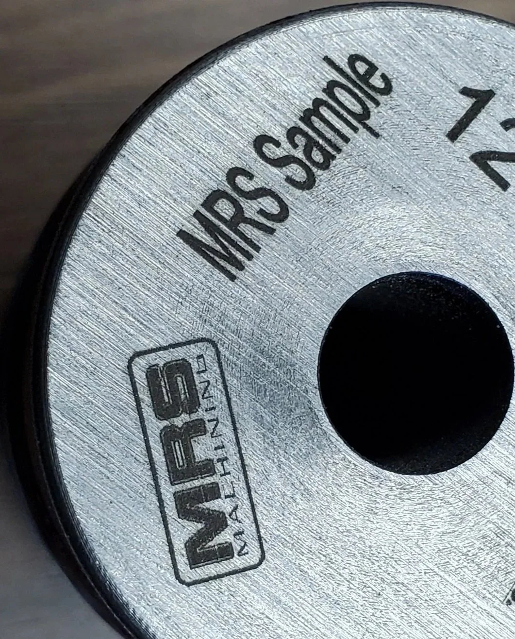 precision laser marking on machined metal part with logo and serial text