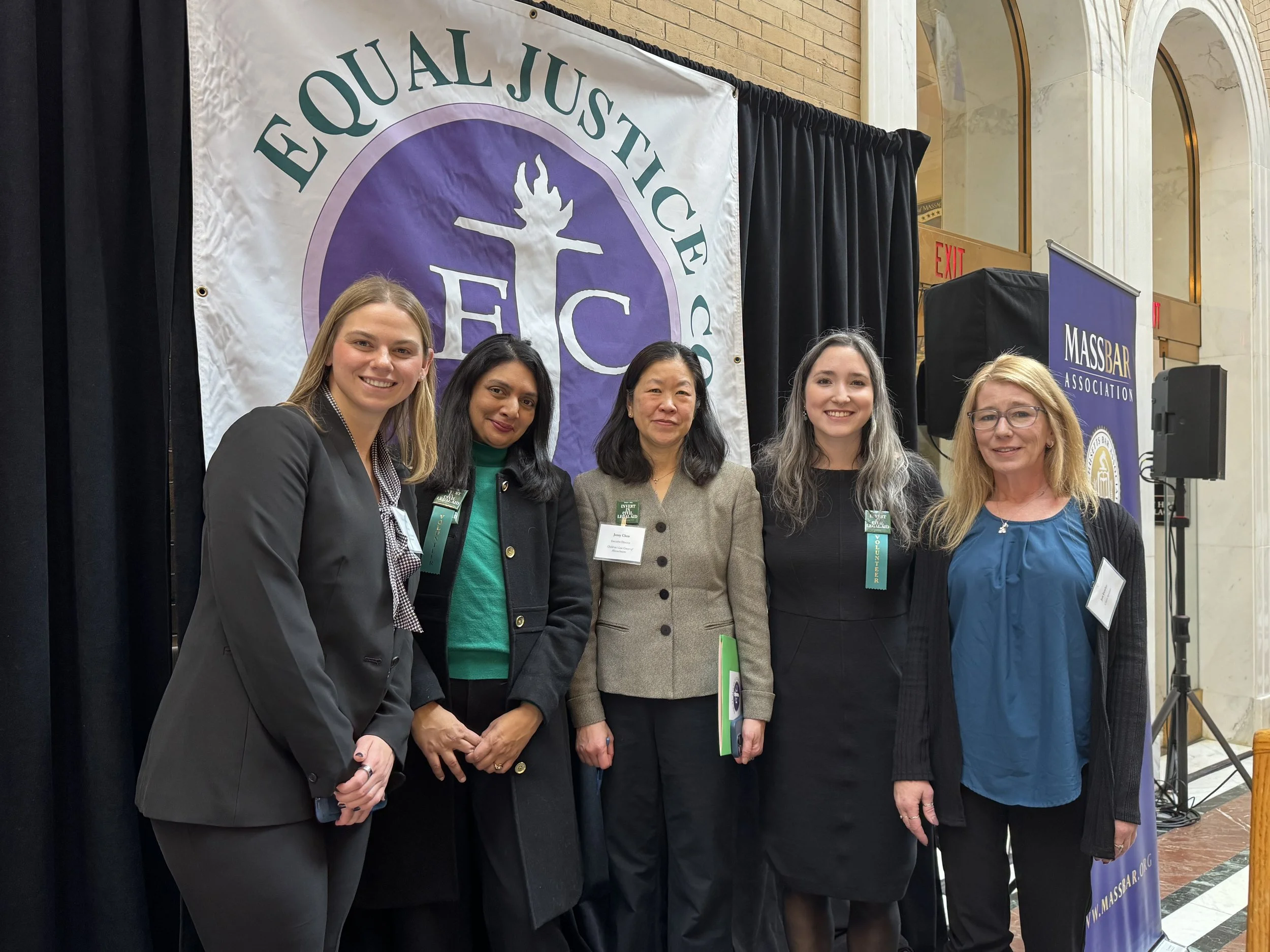 Five women stand in front of Equal Justice Works banner at State House