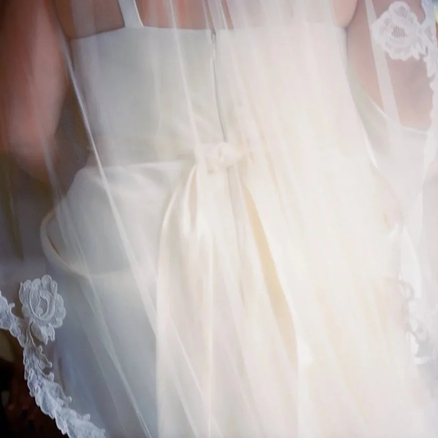 Close-up of a bride's white wedding dress with lace details and sheer fabric.