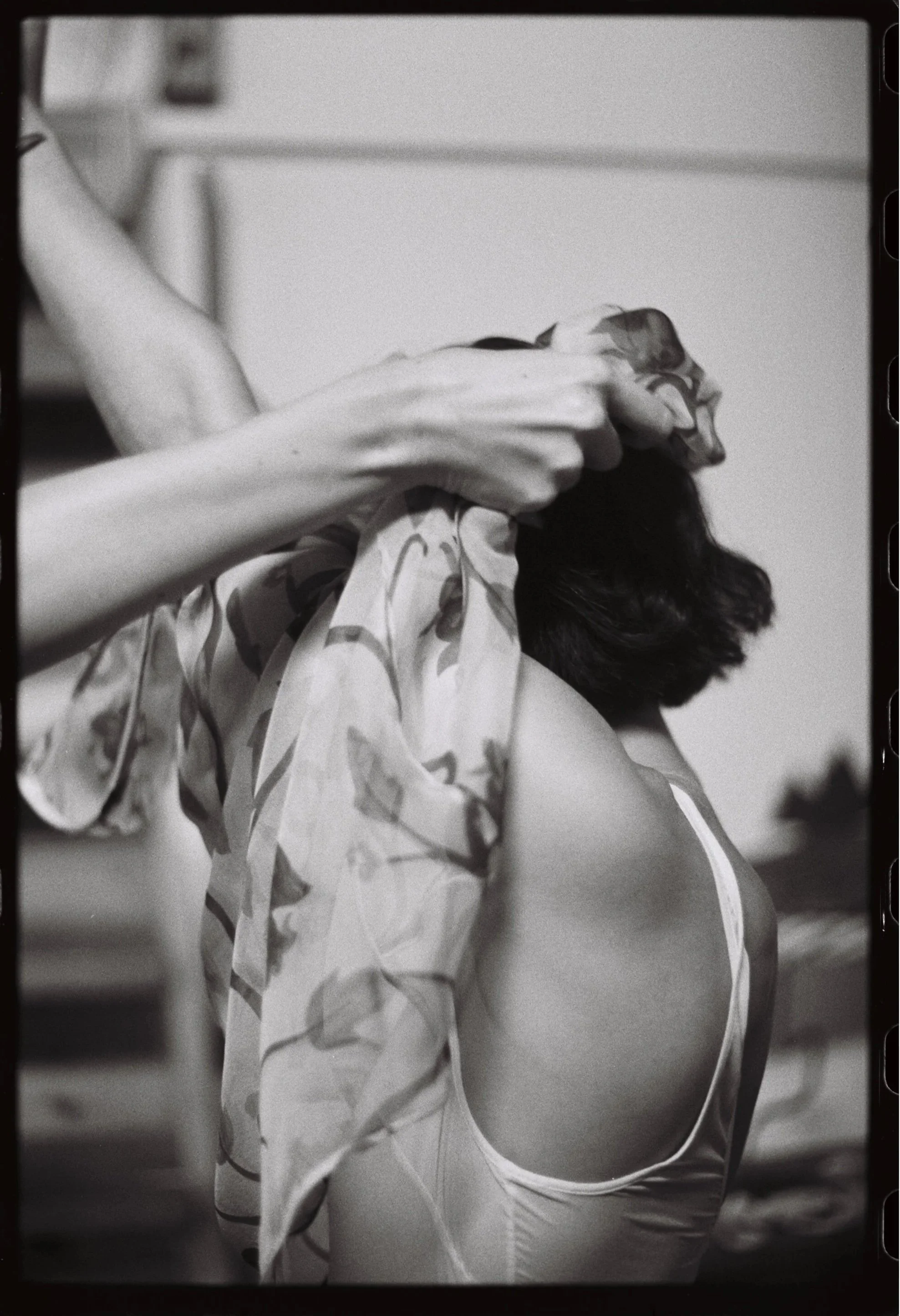 A person dressed in a leotard getting their hair styled with a fabric scarf. Non -traditional film wedding photographer in Maine. 