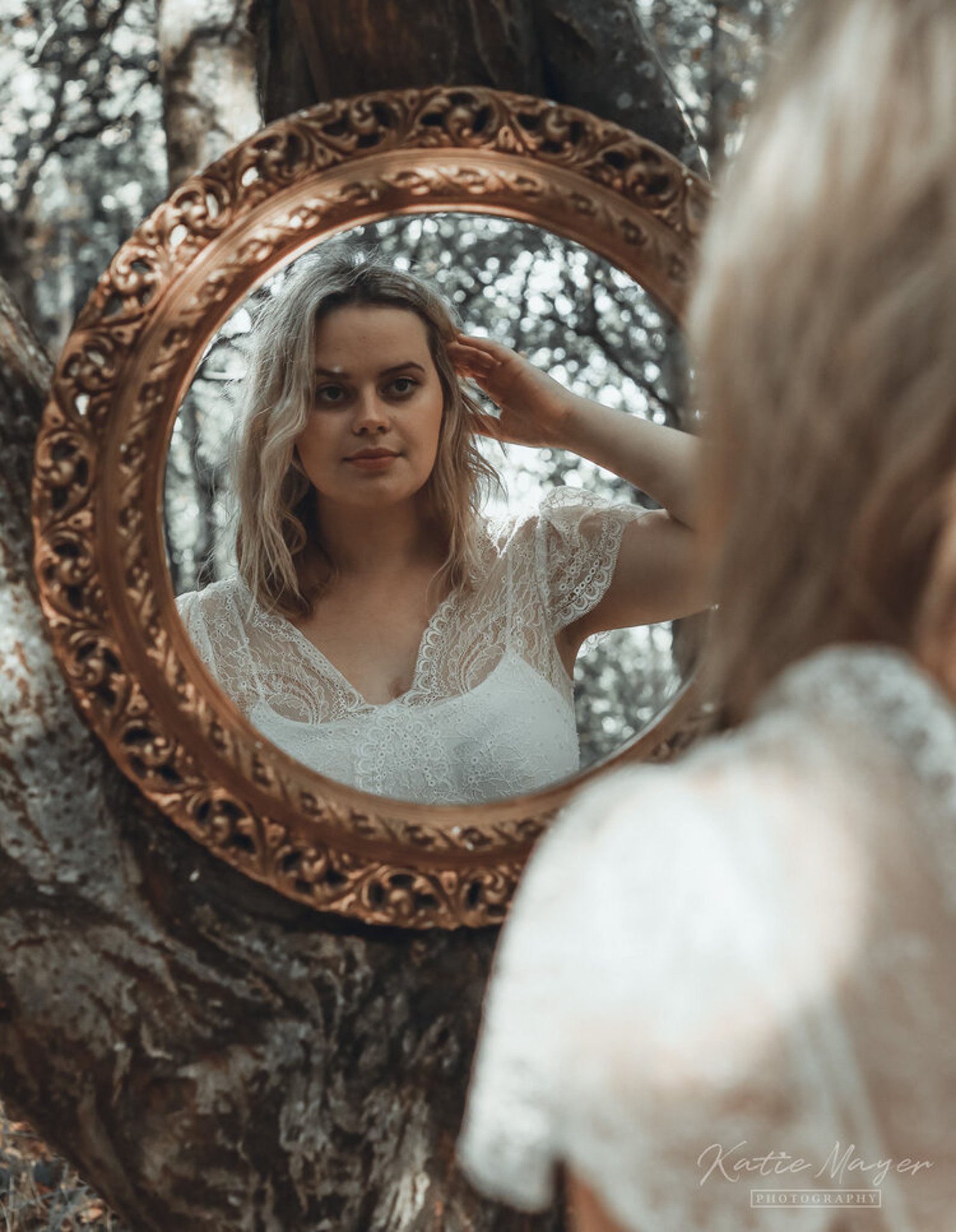 A bride checking hair hair in the mirror whilst standing in the woods during stylised photoshoot in Buckingham