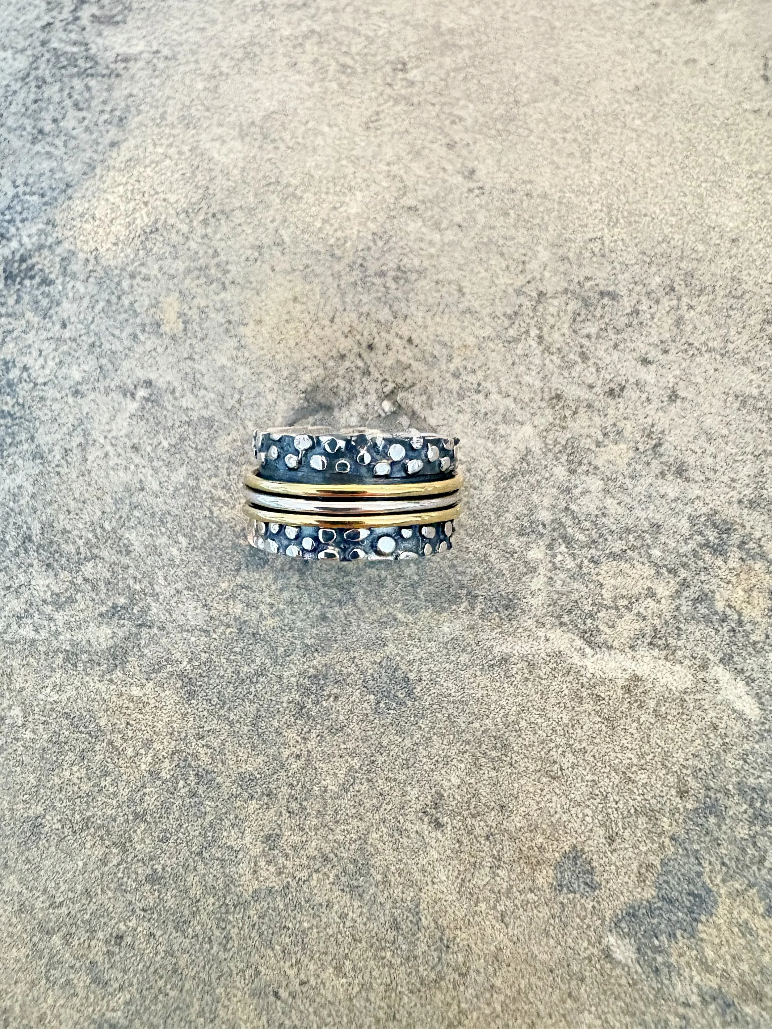 A pile of rings resting on a textured surface with a beige and gray tone.