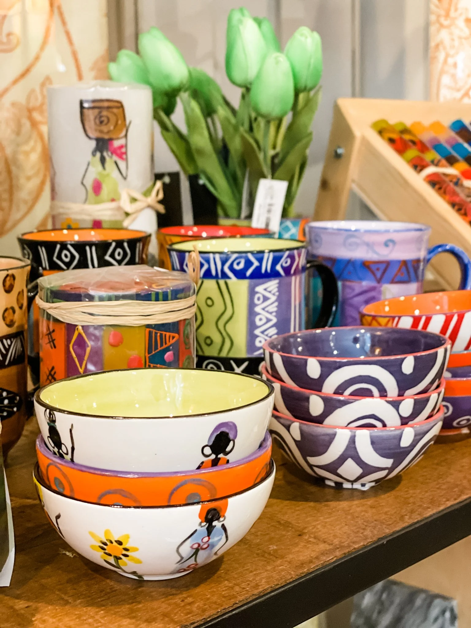 Colorful decorative ceramic bowls on a wooden surface with a small potted plant in the background.