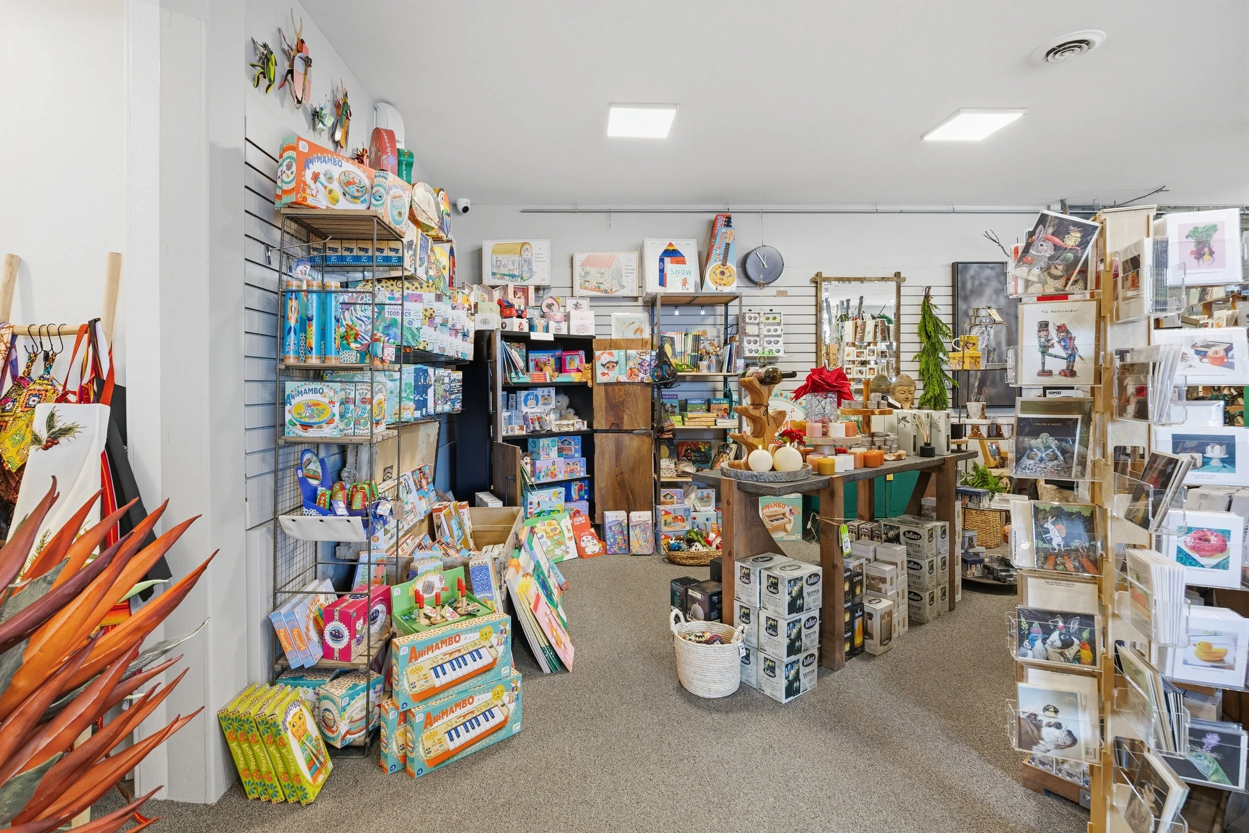 Interior of a gift or novelty store with shelves filled with toys, stationery, artwork, candles, and decorative items.